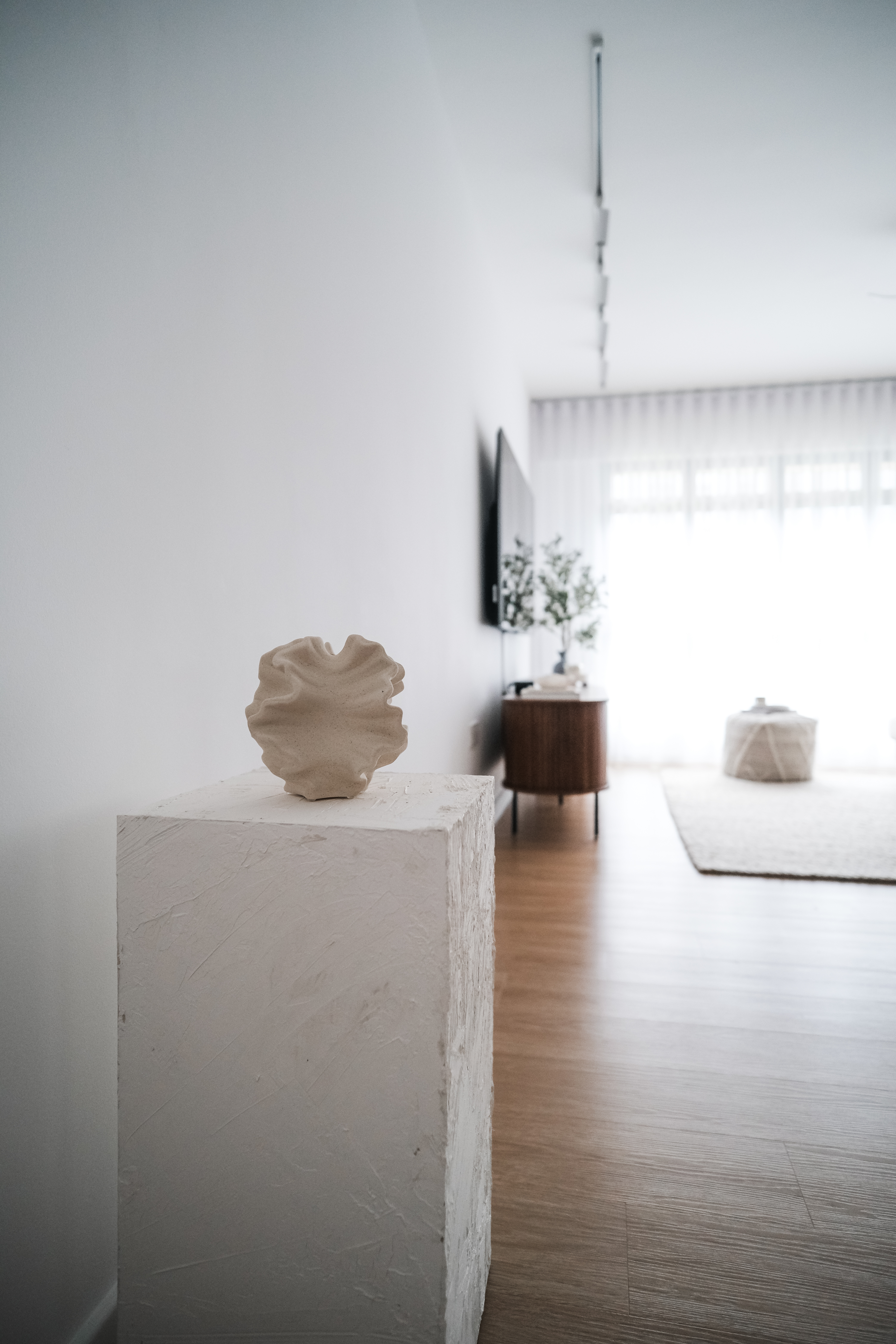 Comfort in Style: How $3.5k Loose Furniture Elevates CozyLiving Room - Minimalist art piece on white pedestal, modern living