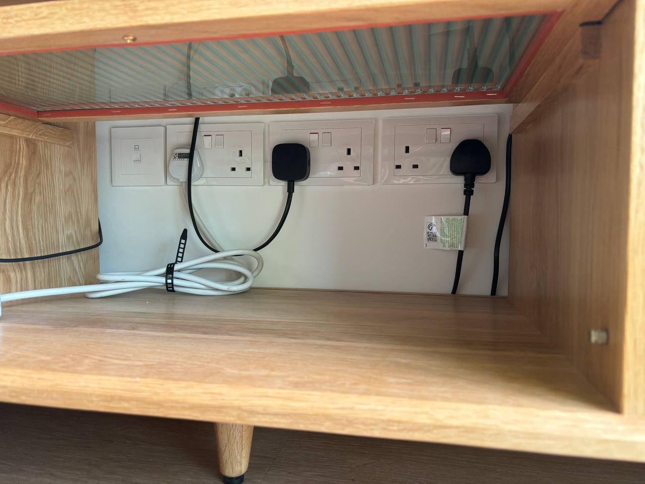 Our Living Room: When Curves and Green meet - Wooden cabinet, electrical outlets, white wall sockets, black power strips
