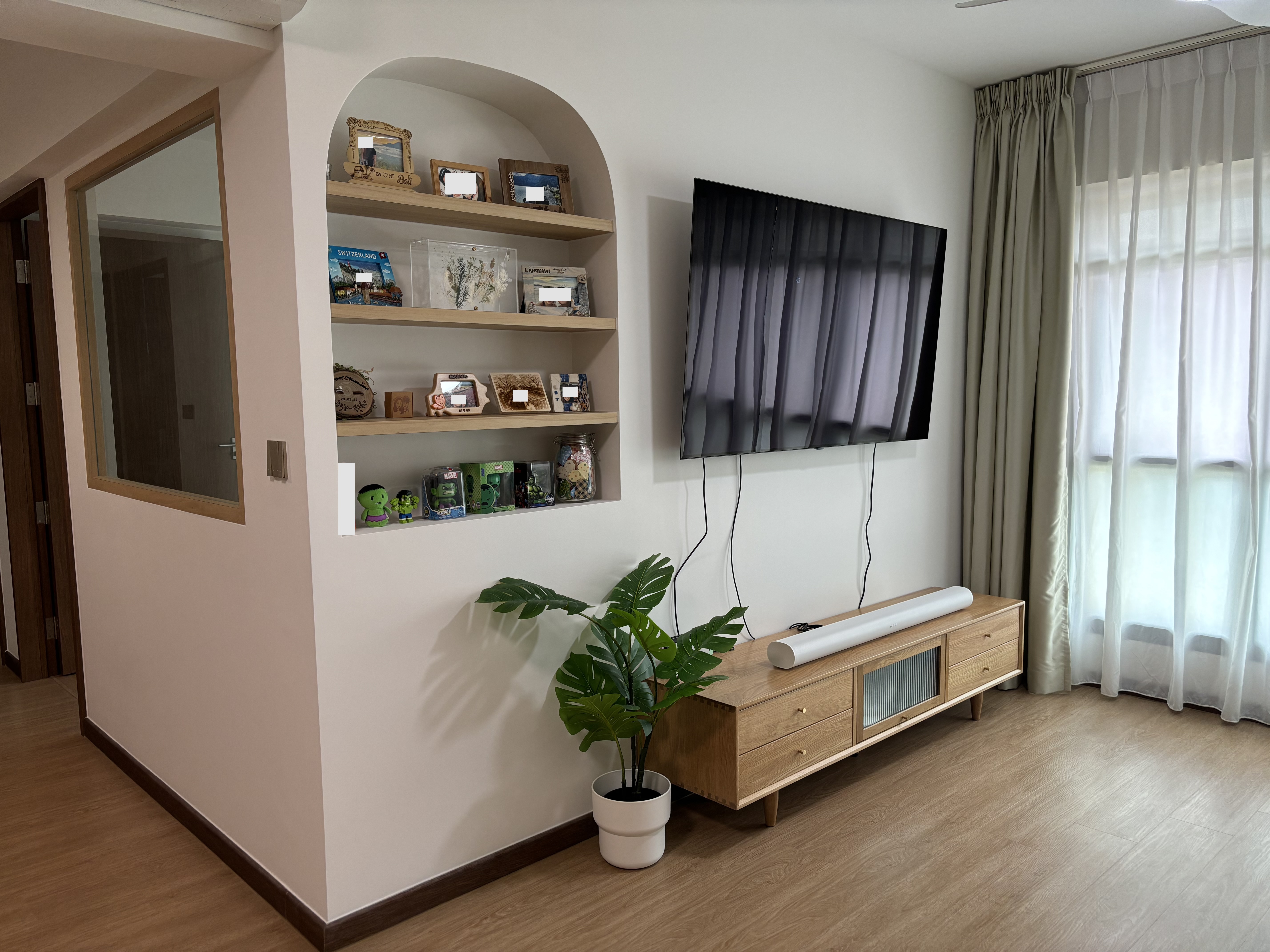 Our Living Room: When Curves and Green meet - Wooden shelf with framed photos, green toy figures, clear glass aquarium, black