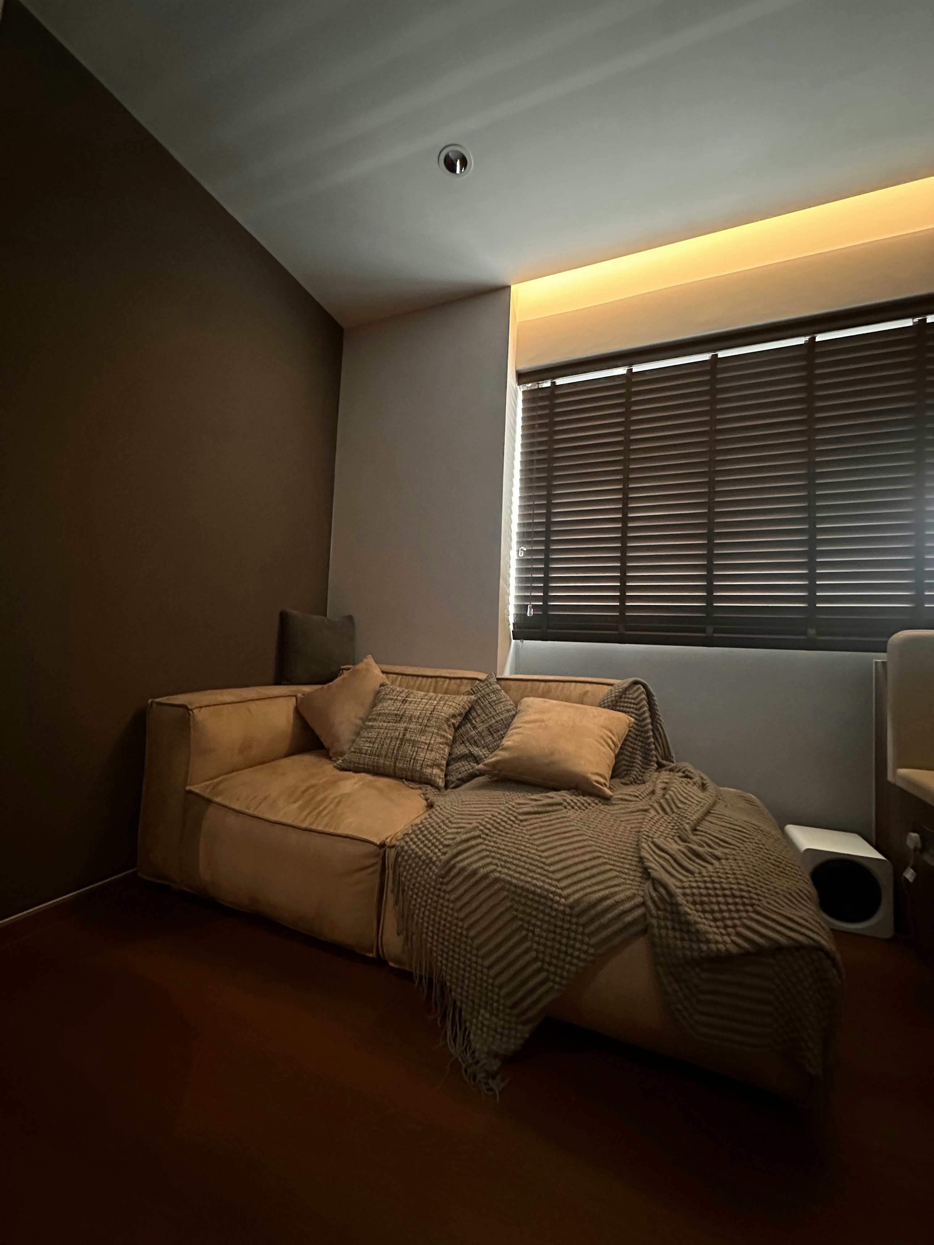 Lounging Area with a Warm Glow✨ - Modern living room, cozy sofa, beige cushions, textured blanket, soft lighting, dark brown