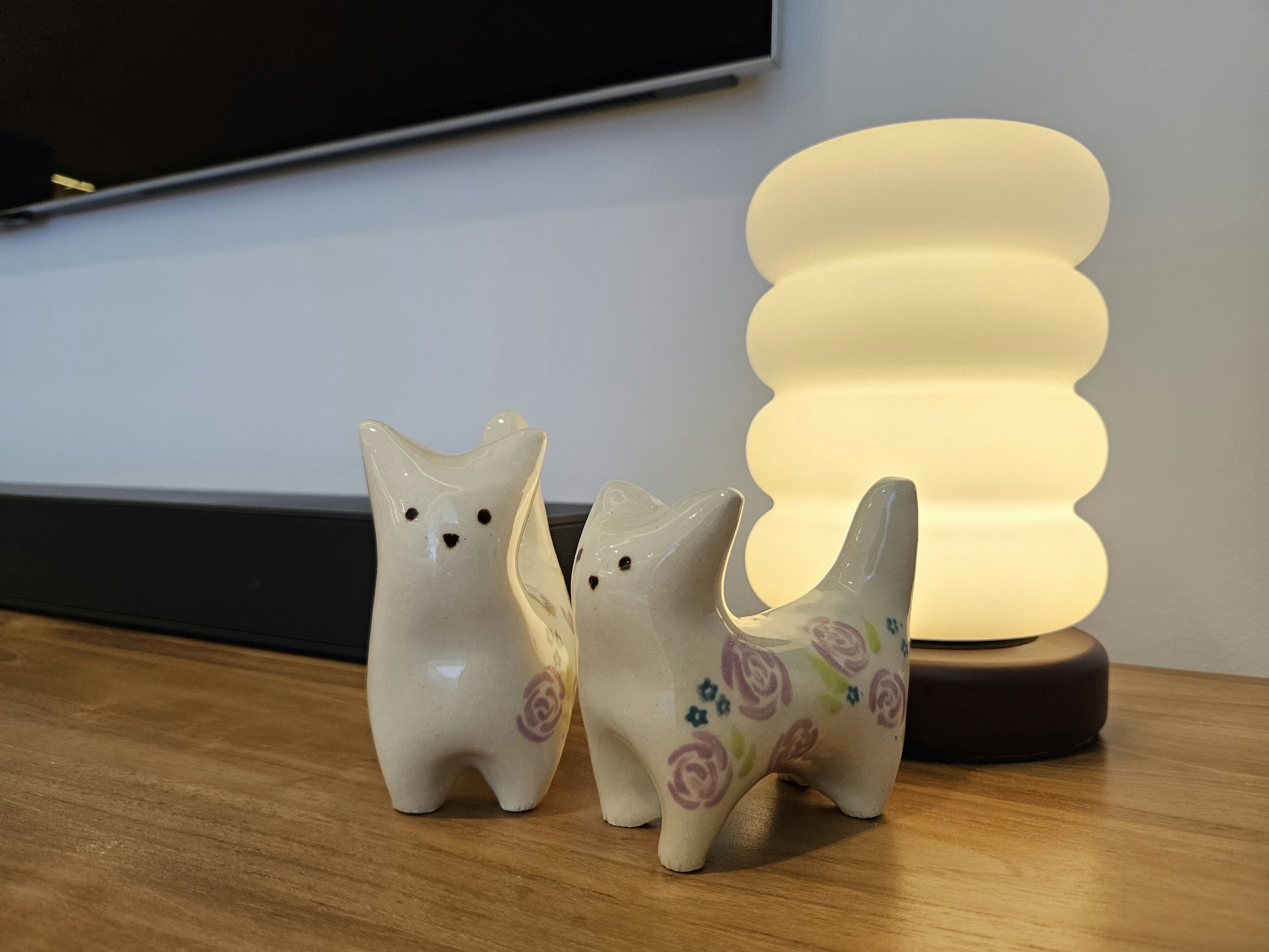 Maximising Space In Our 5m Long Living Room - White ceramic cat figurines with black eyes and small black nose, adorned with