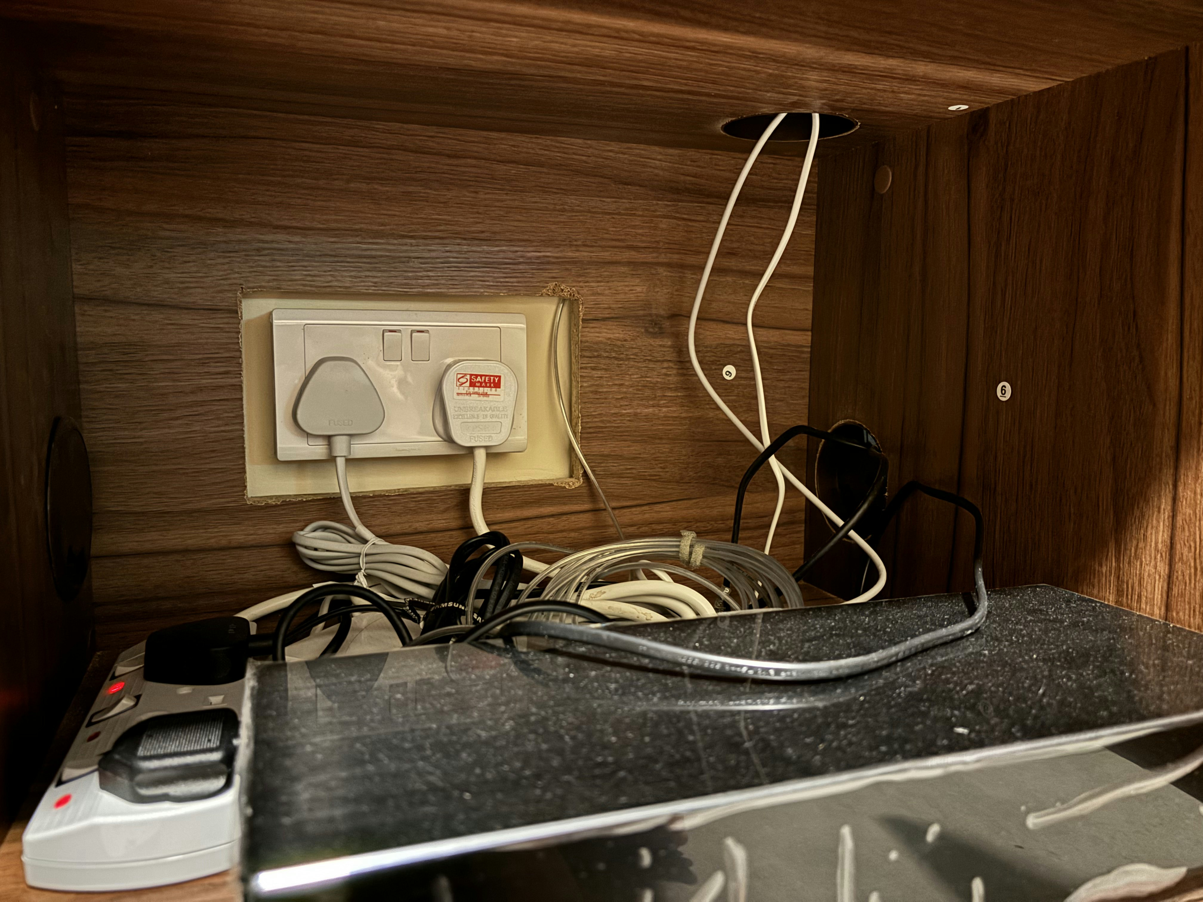 Our living room budget hack: "built in" TV console for just $250 - Wooden wall, electrical outlet, white plug, grounding