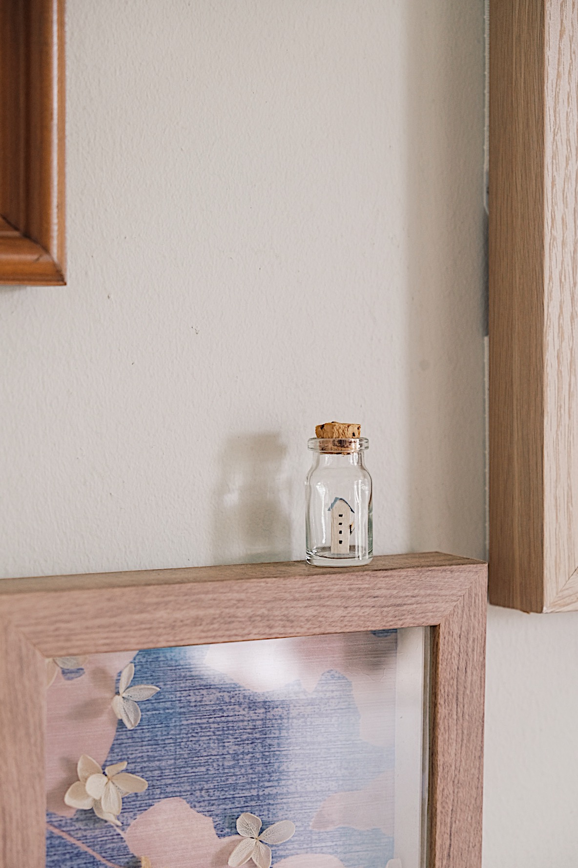 Styling gallery walls filled with memories in our Living Room (+TIPS) - Glass jar with house illustration, wooden frame