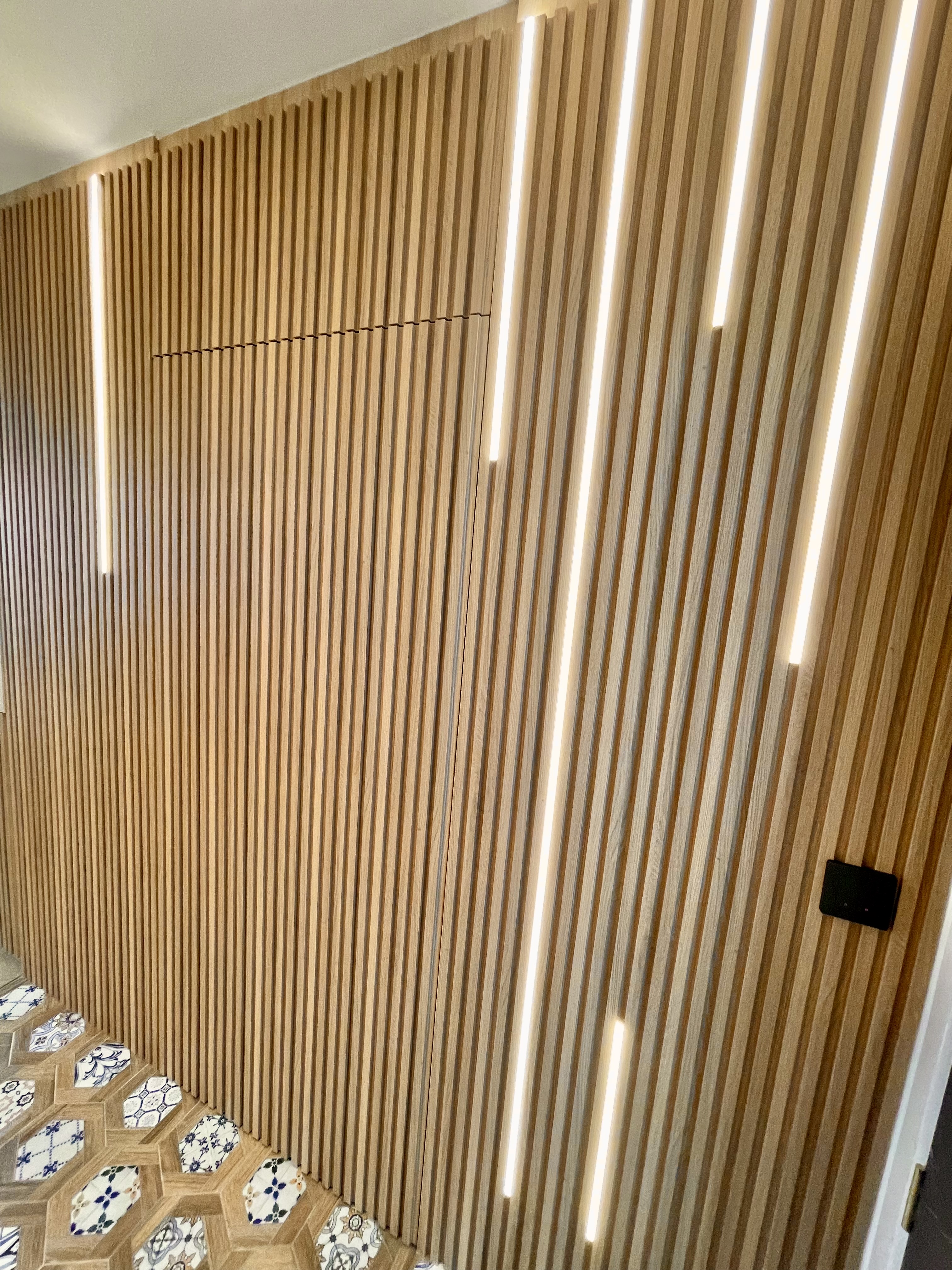 Our Entryway: An Amalgamation Of Peranakan Tiles & Tempered Glass Gate - Wooden wall with vertical slats, illuminated by