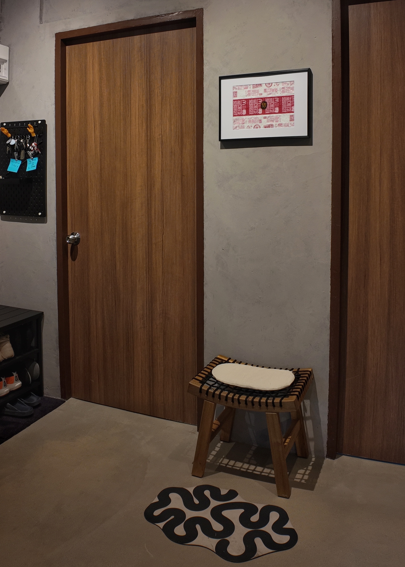 Enter this way folks! - Wooden door, black pegboard, blue sticky notes, shoe rack, black and white rug, wooden stool