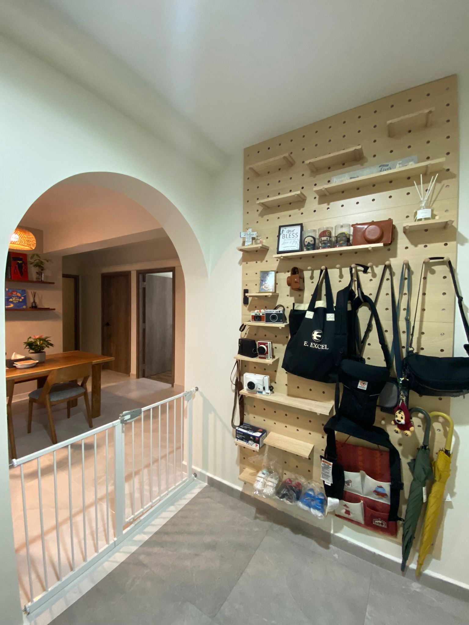 An entrance to an enchanting home, sets tone for guests - Wooden pegboard wall, assorted bags, camera, figurines, small