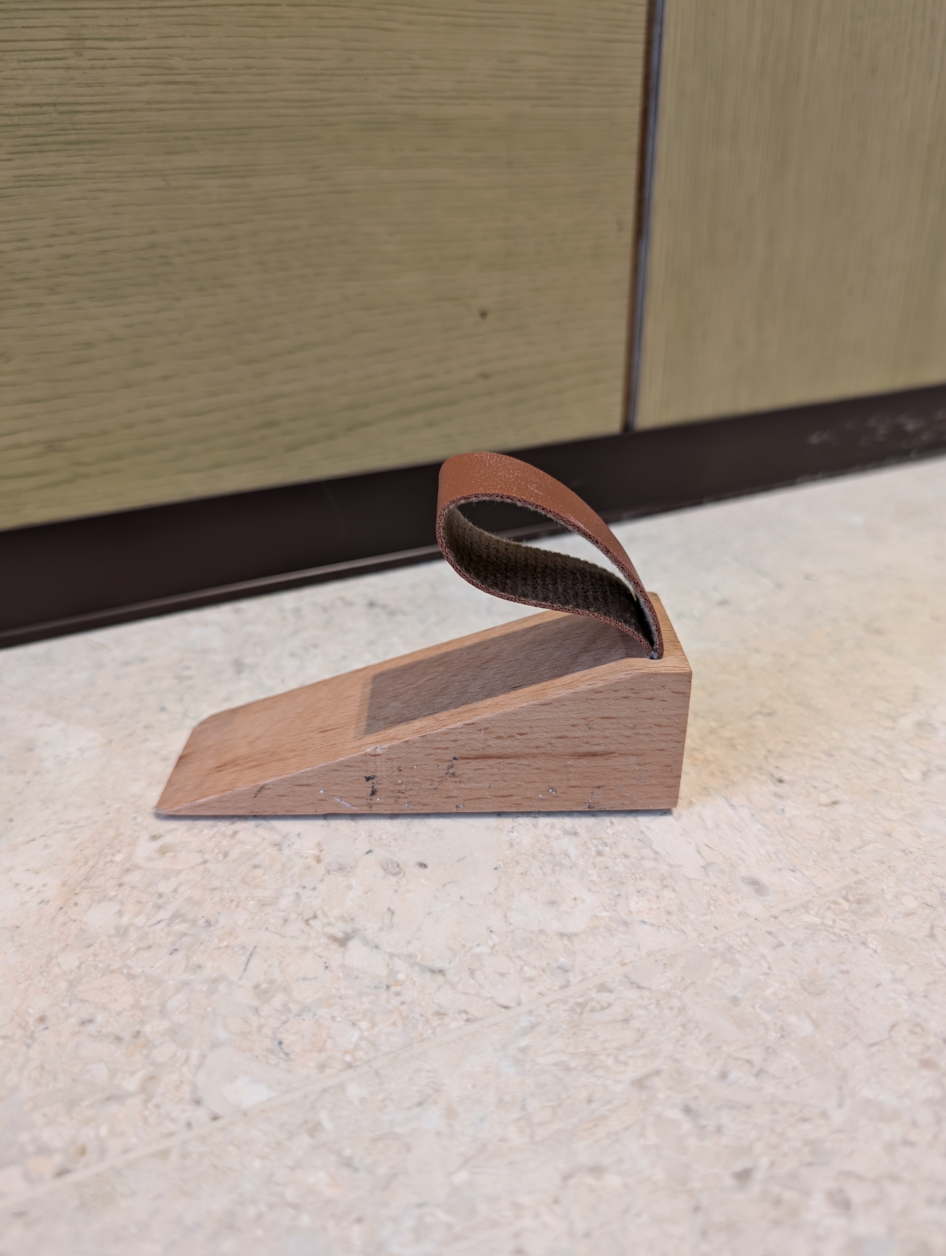 Huh you have 3 shoe cabinets?? 🐛🐛 - Wooden shoe sole with brown leather strap, textured surface, light-colored marble