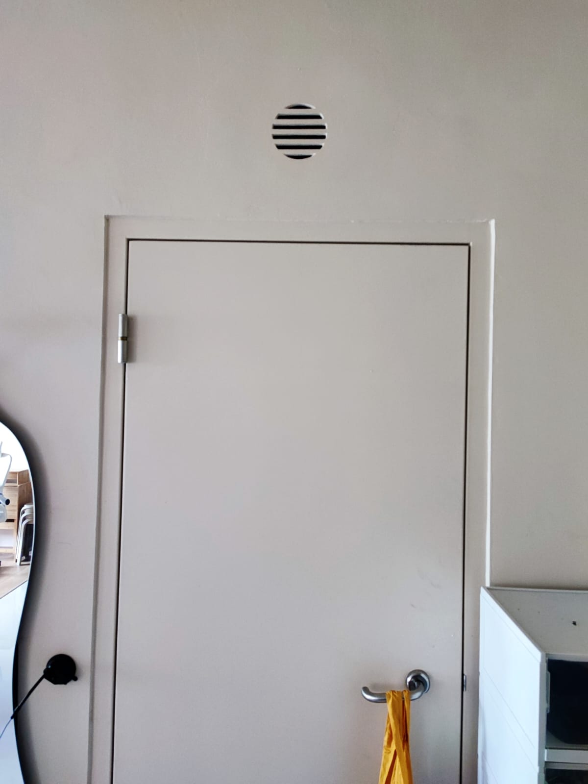 A functional entryway - Using paint to conceal unsightly areas! - White door with circular vent, yellow towel hanging