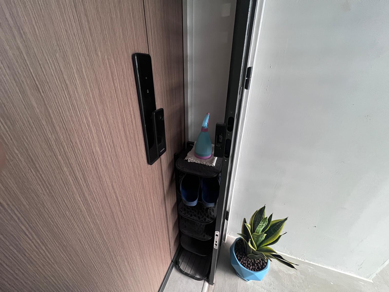 A simple & functional entryway with built in settee - Wooden door, black handle, small shelf, blue spray bottle, black shoes
