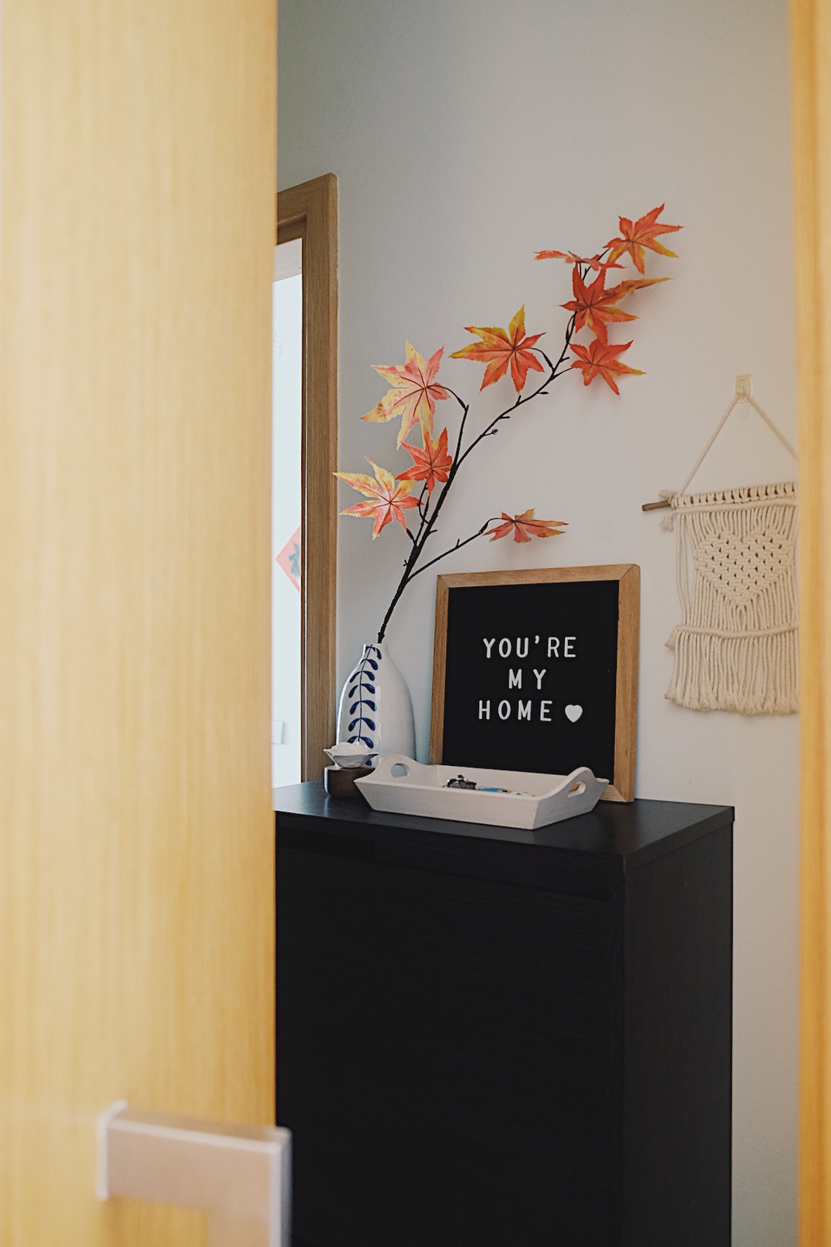 Cube-sized Foyer in a Dual-key Apt with a shoe rack and decor touches - vibrant autumn leaves, cozy interior, decorative wall