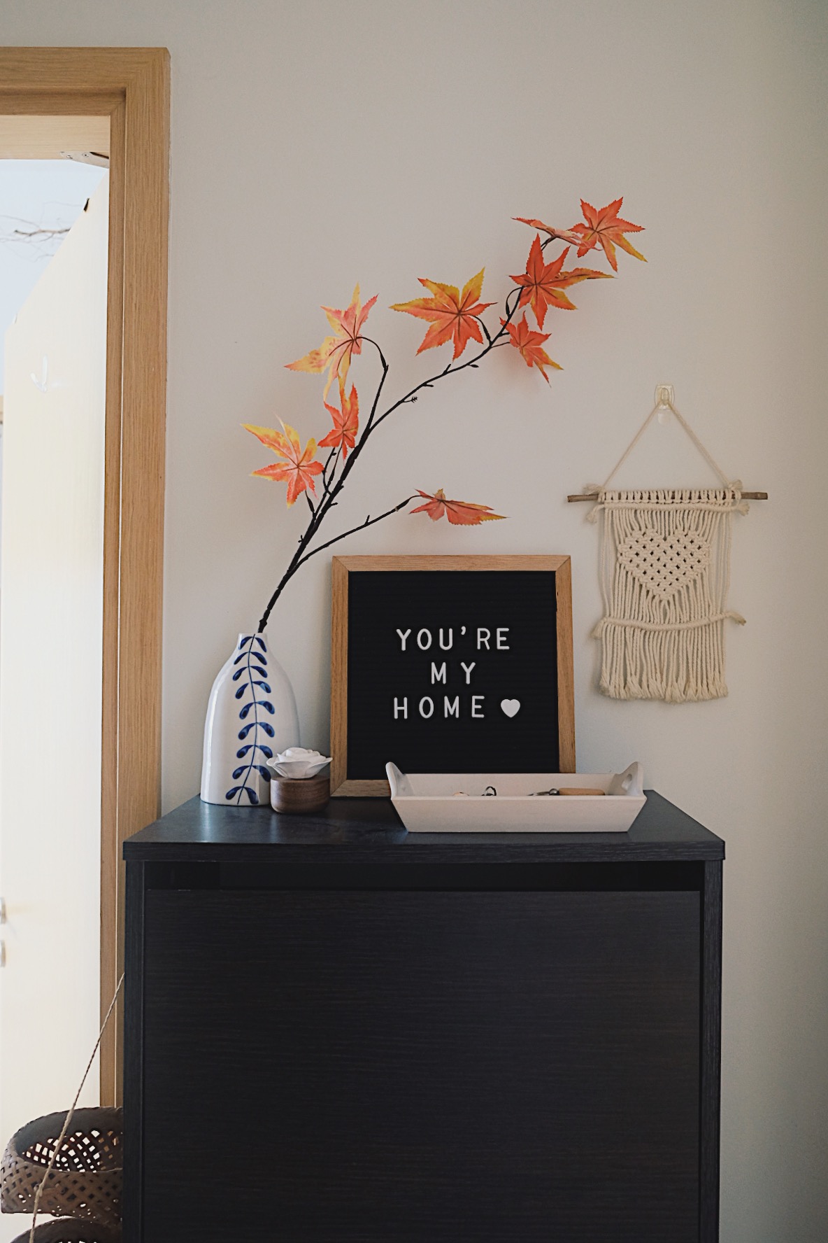 Cube-sized Foyer in a Dual-key Apt with a shoe rack and decor touches - vibrant autumn leaves, blackboard message, "You're My