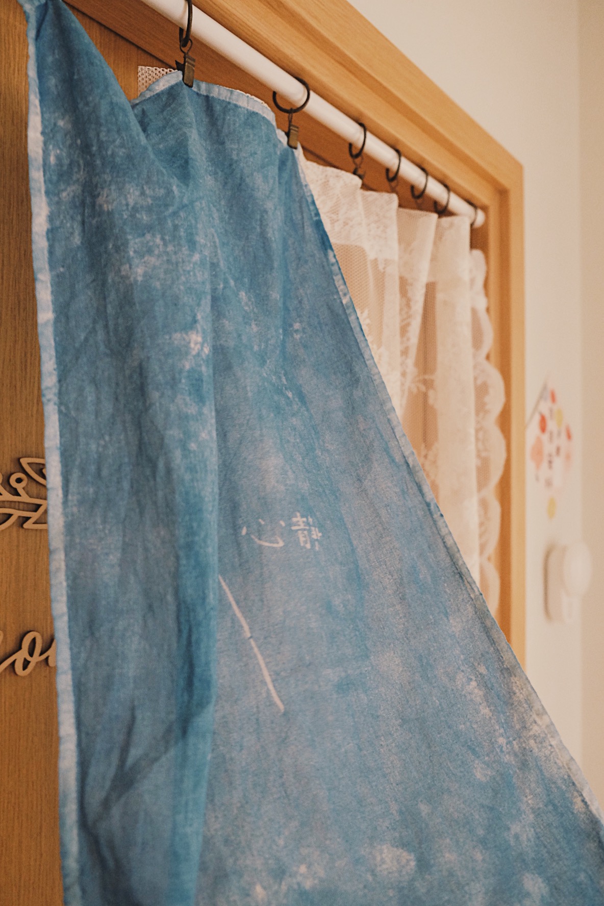 Cube-sized Foyer in a Dual-key Apt with a shoe rack and decor touches - Blue fabric towel, hanging on wooden rack, white lace