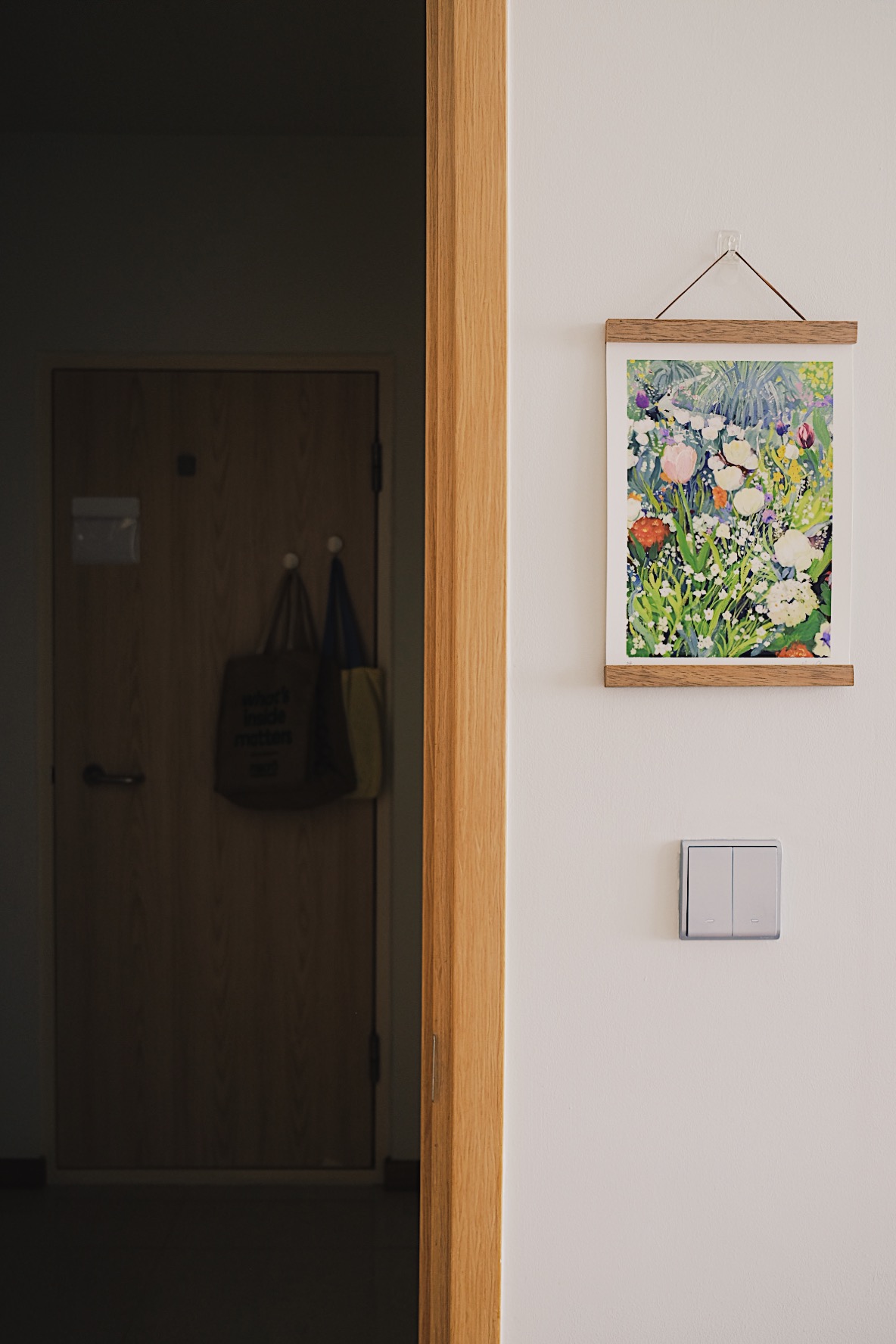 Cube-sized Foyer in a Dual-key Apt with a shoe rack and decor touches - Wooden door, hanging bags, abstract painting, light