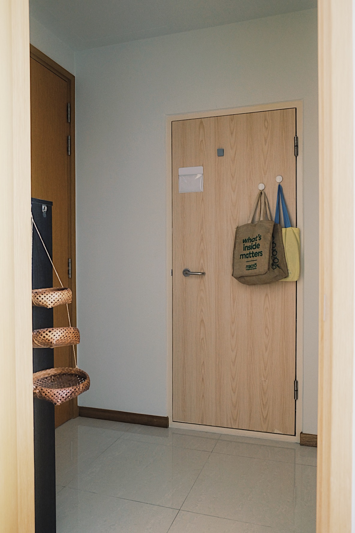 Cube-sized Foyer in a Dual-key Apt with a shoe rack and decor touches - Wooden door, beige wall, light gray floor, woven