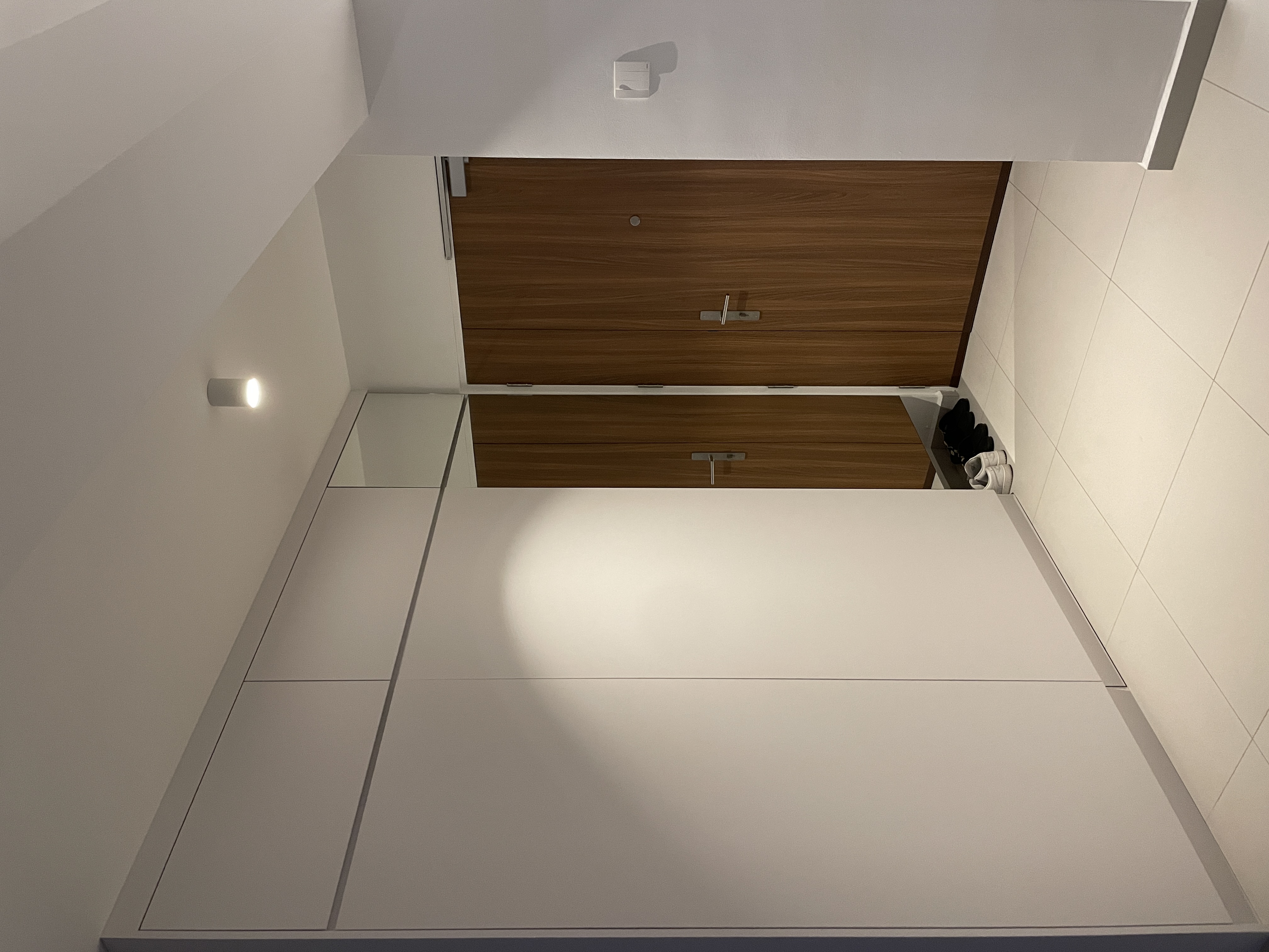 Inviting Entryway: Concealed Bomb Shelter and Shoe Storage - Wooden cabinetry, minimalist design, white walls, modern