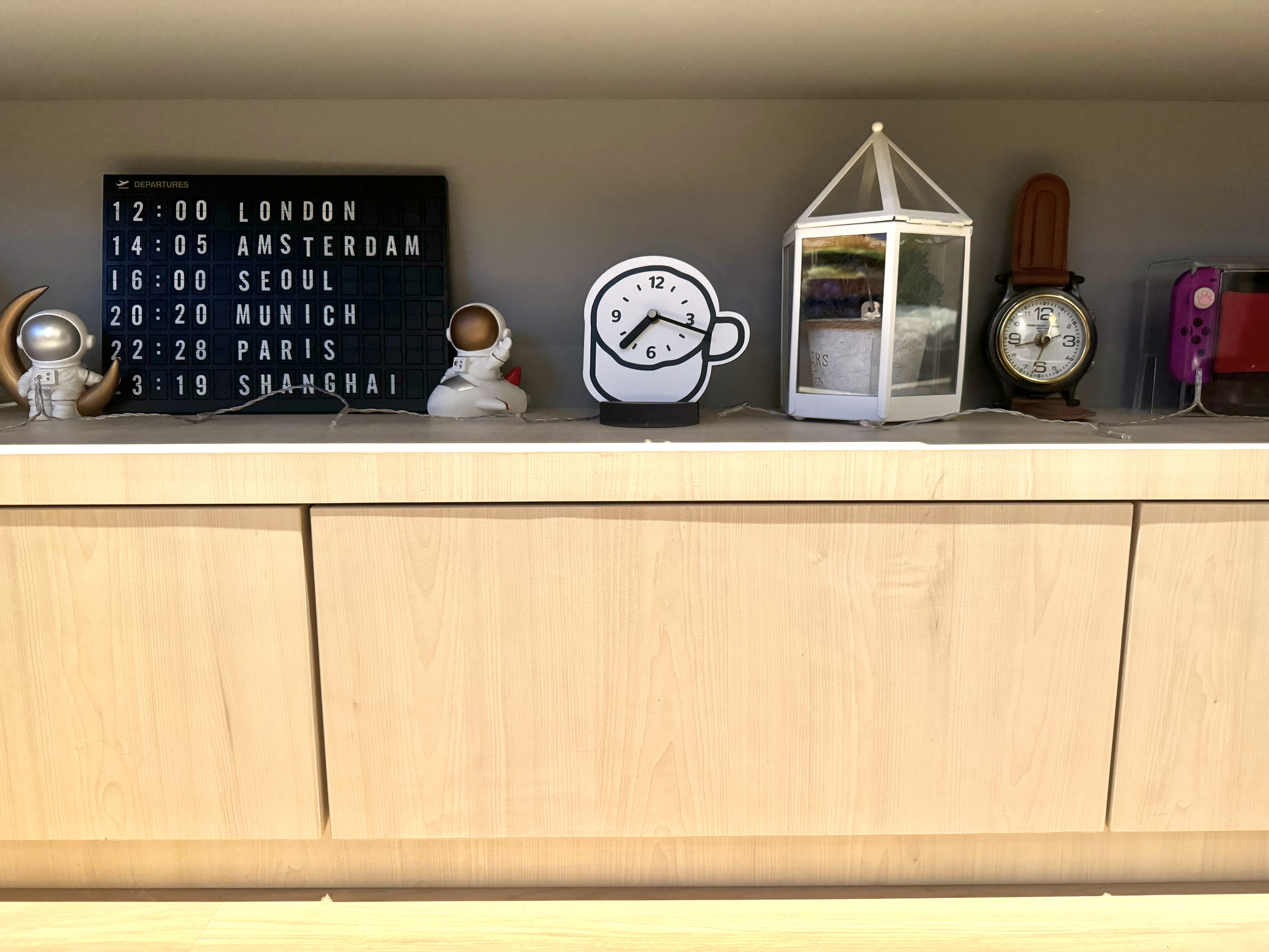Peek-A-Boo Spaces to Maximise 93sqm - Wooden shelf with various clocks and figurines, Blackboard displaying departure times