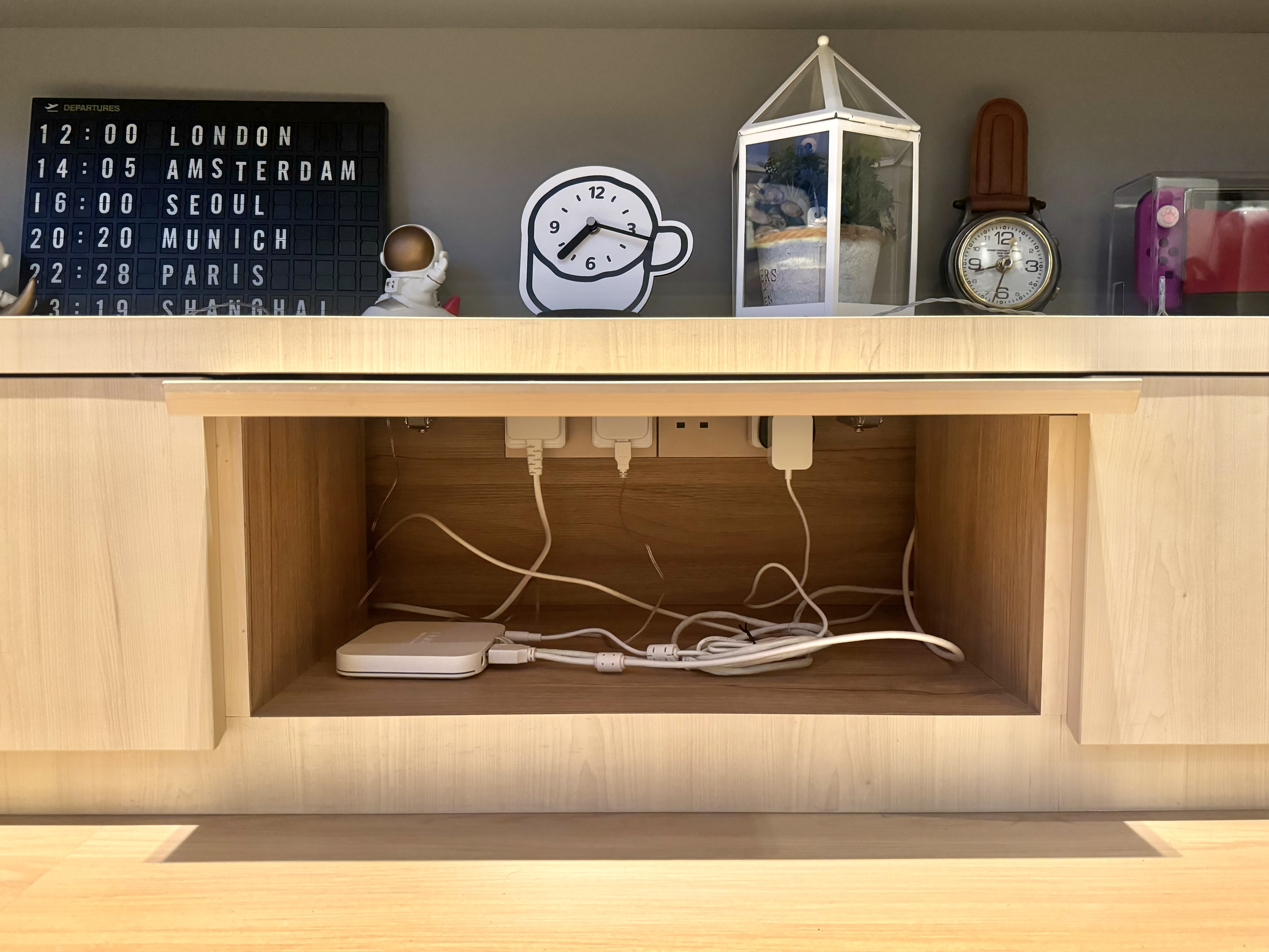 Peek-A-Boo Spaces to Maximise 93sqm - Wooden shelf with neatly organized cables and devices, Clock displaying time with a