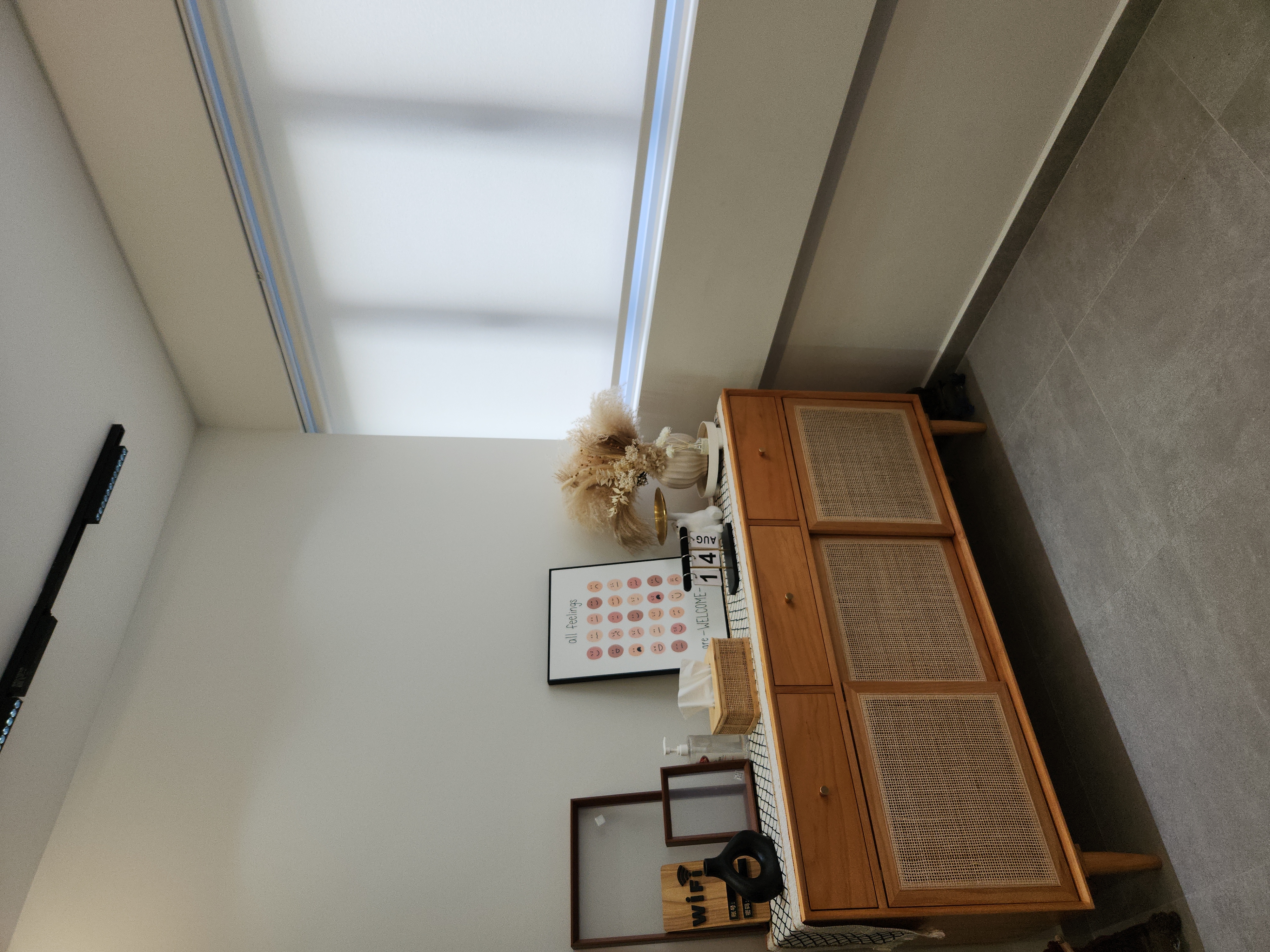 No build-ins for our Entryway - sunlight streaming through window, wooden cabinet with woven baskets, decorative vase with