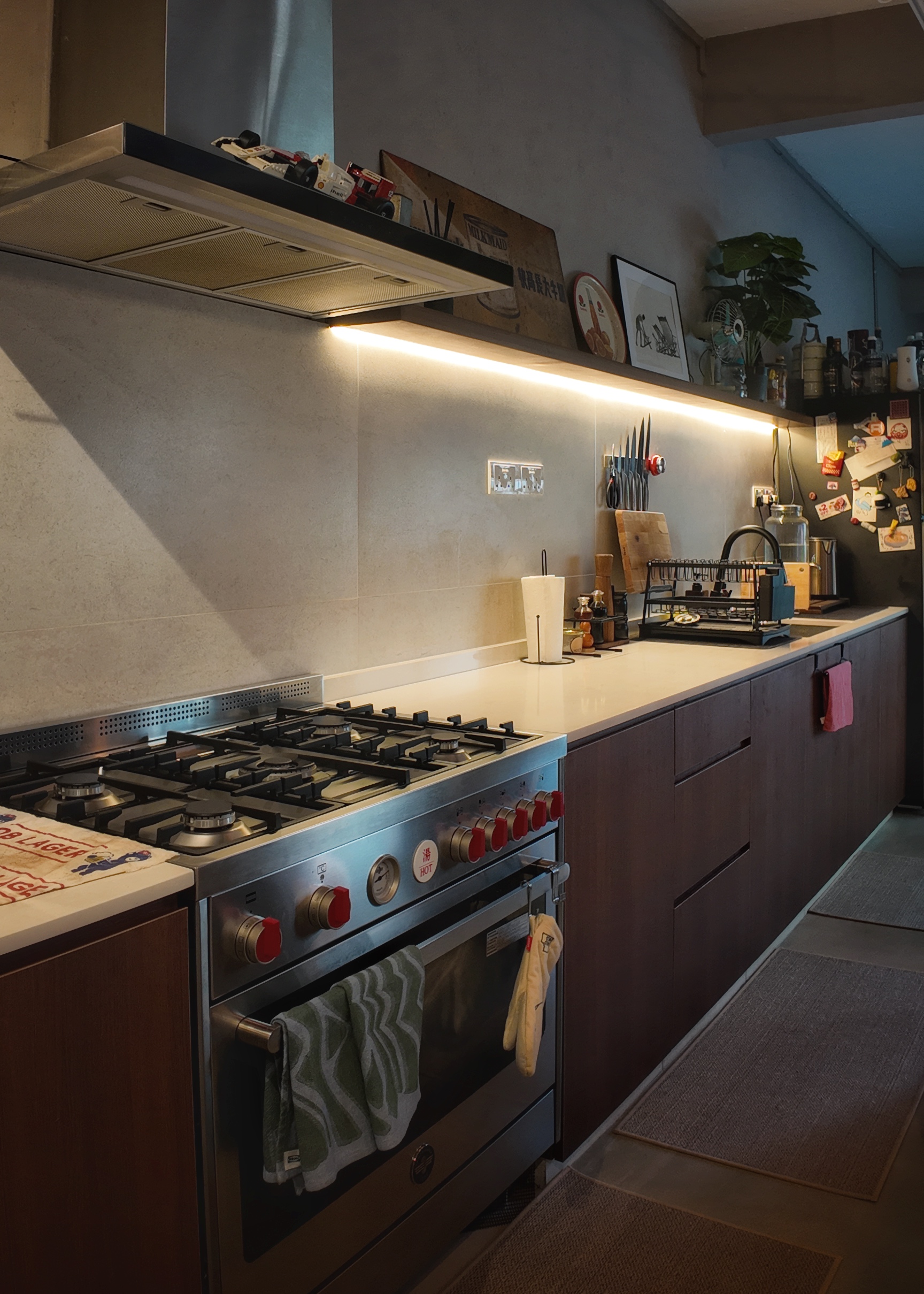 This is where food babies are made - Modern kitchen with stainless steel gas stove, red oven knobs, and green towel hanging.