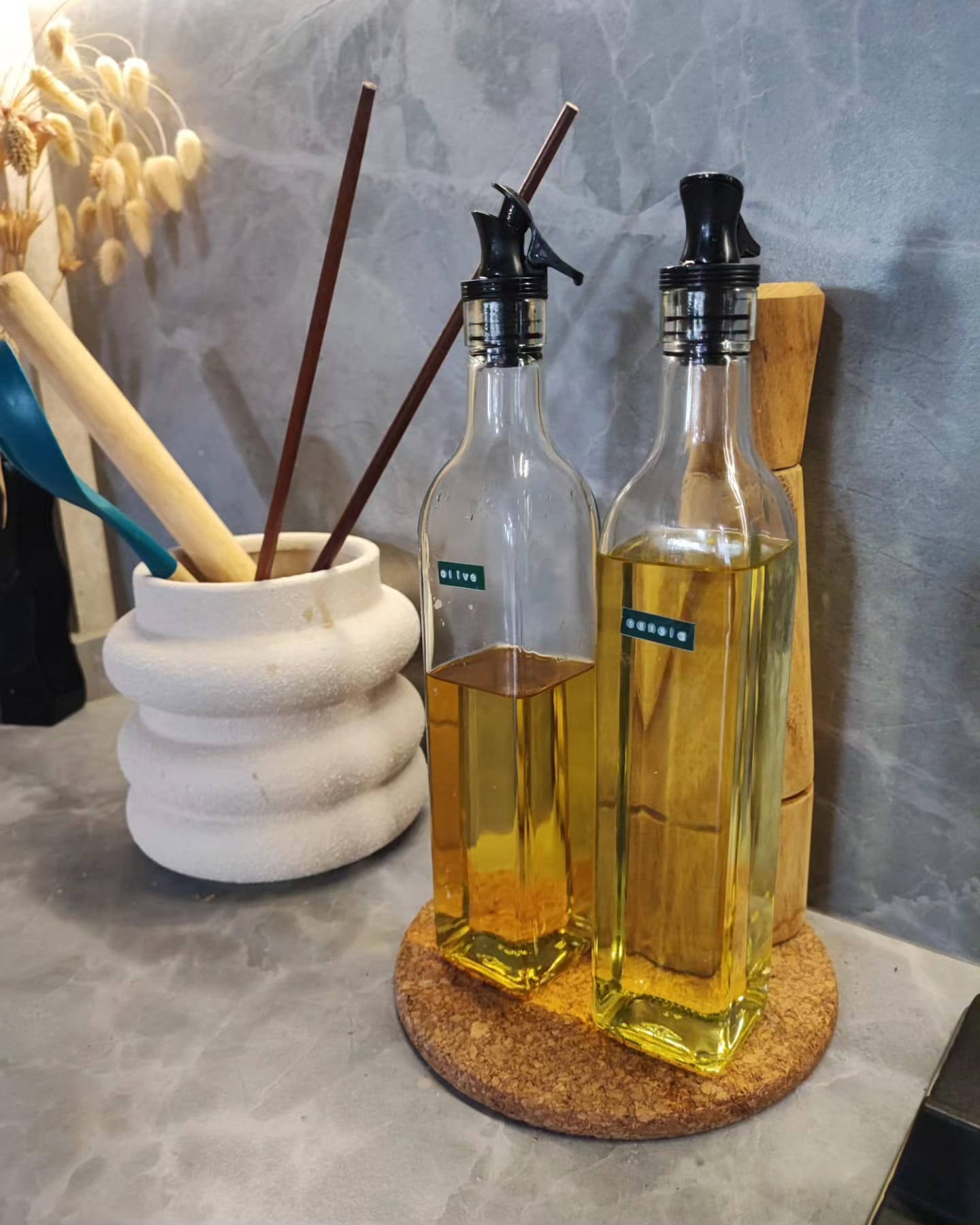 A Low-Cost & Open Concept Kitchen with Stone and Industrial Touches - glass bottles, yellow liquid, wooden coaster, natural