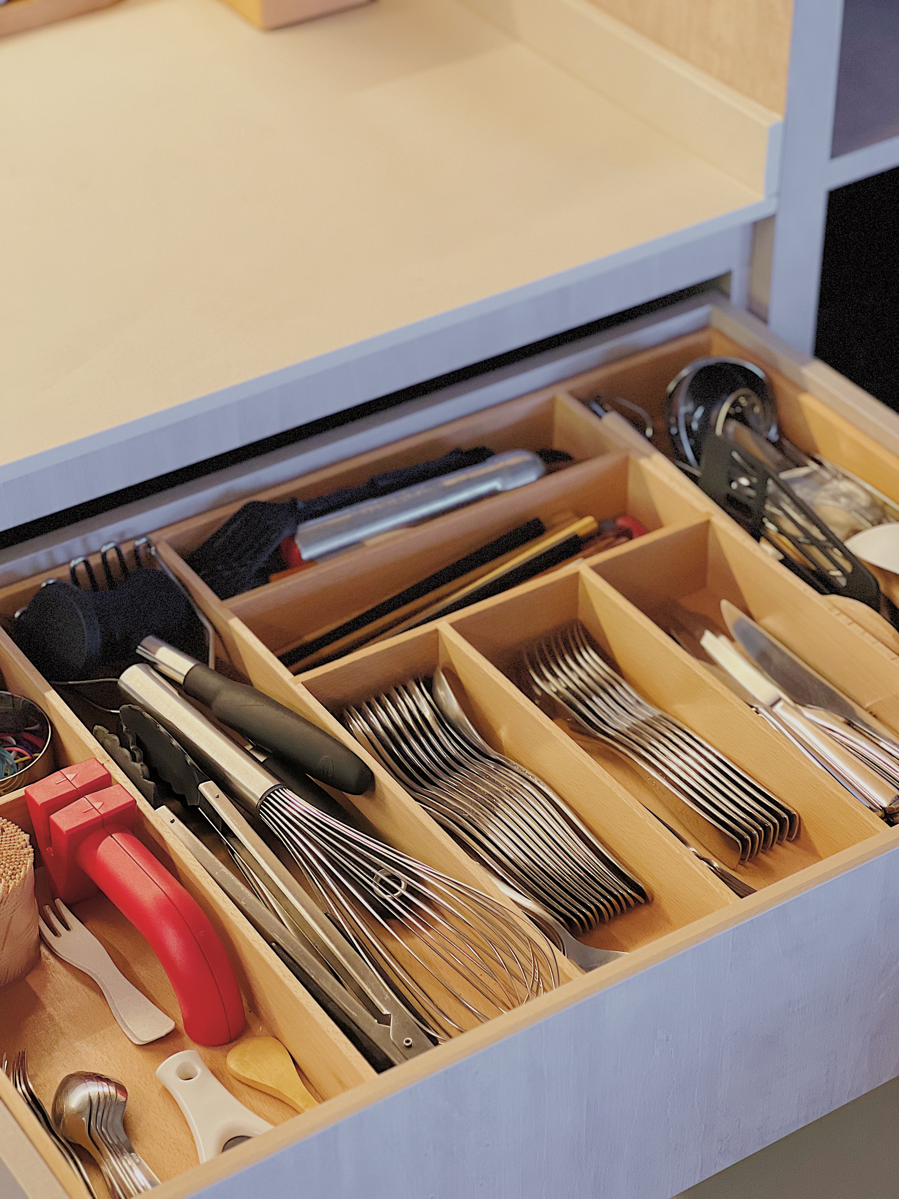 Whipping Up Meals on our Peninsula Stove - Wooden kitchen drawer, neatly organized utensils, stainless steel knives, red
