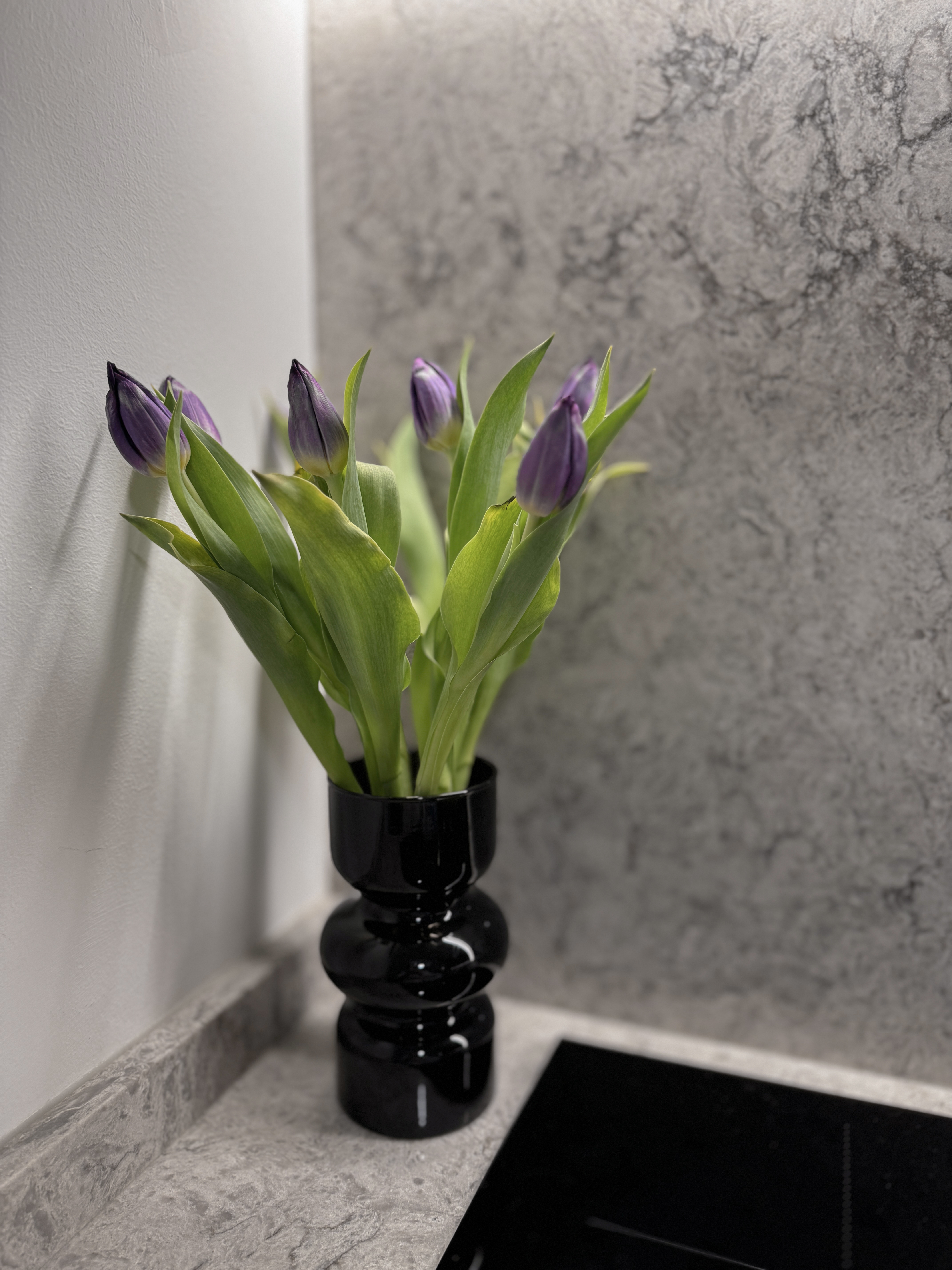 Sleek Open Concept Kitchen: Warm Tones with Minimalist Elegance - vibrant tulips in black vase, modern interior decor, fresh