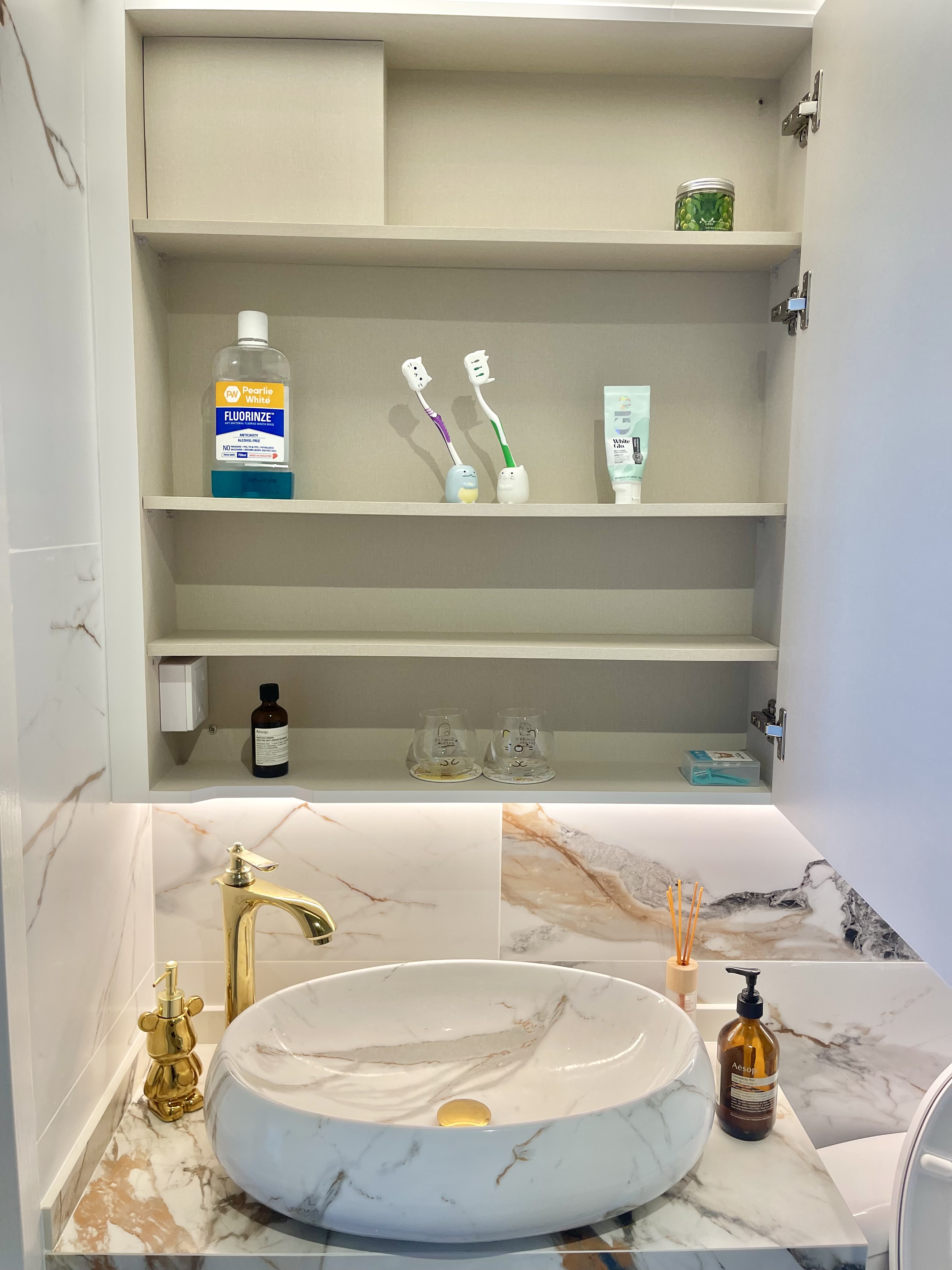 Our Bathroom Sanctuaries: A Concealed Luxe Master Ensuite VS Resort - White marble countertop, gold faucet, white oval sink