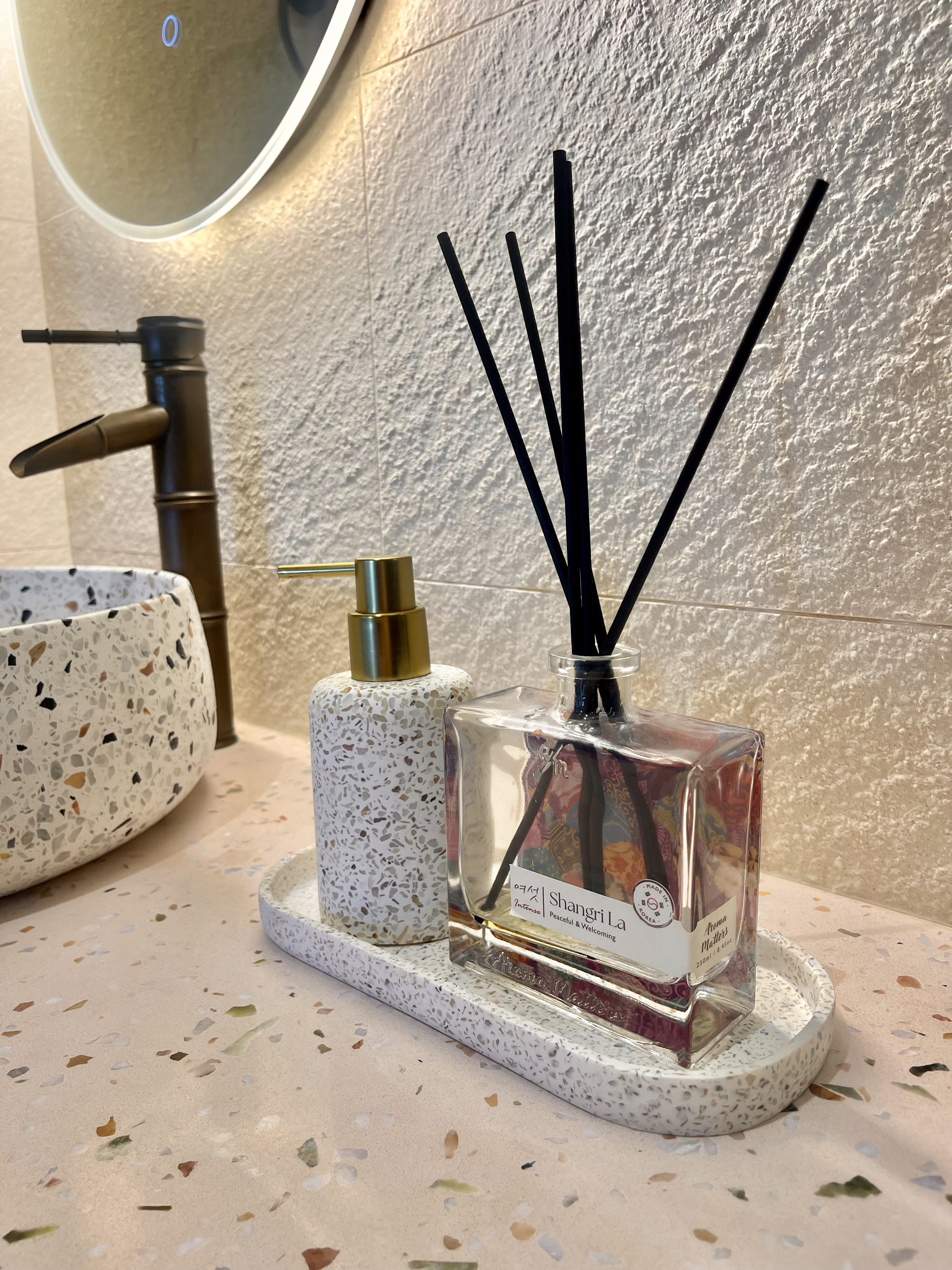Our Bathroom Sanctuaries: A Concealed Luxe Master Ensuite VS Resort - Clear glass perfume bottle with black sticks, speckled