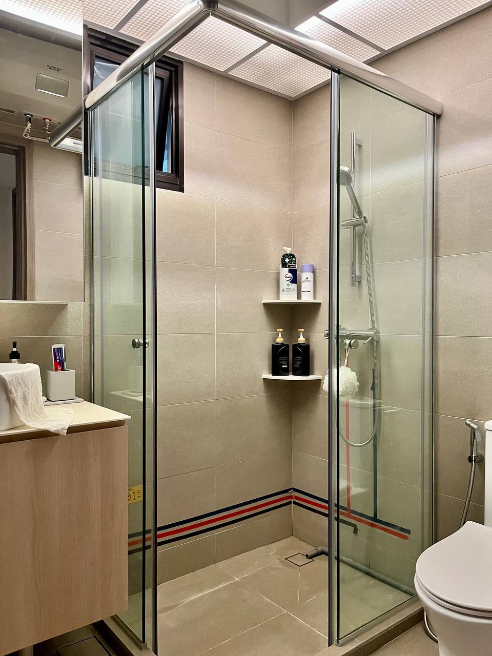 Toilet / Bathroom: Practicality Over Style on a Budget - Glass-enclosed shower, beige tiled walls, modern design, white