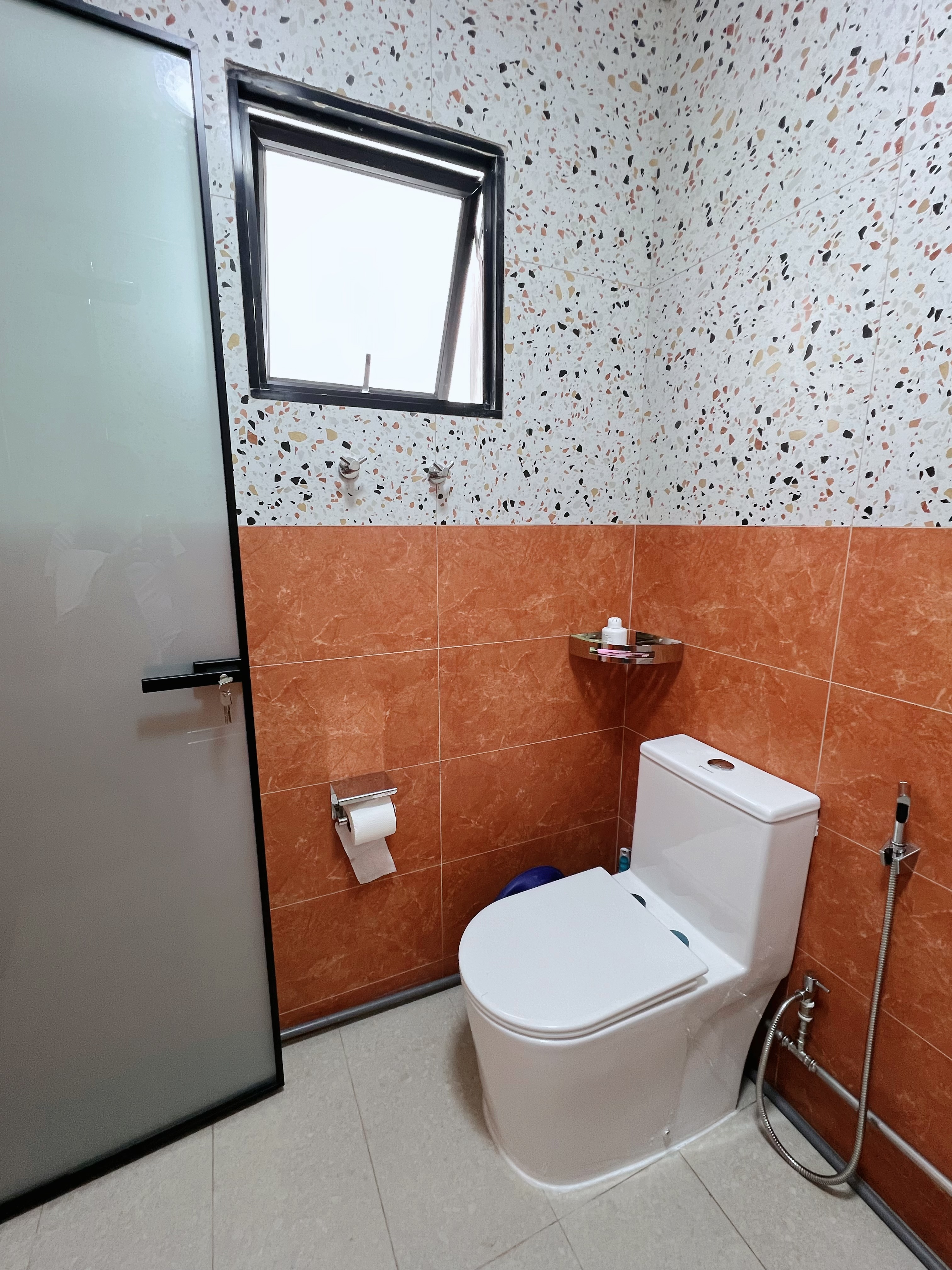 Tile Surprise: A perfect match found! - Bathroom with white toilet, orange tiled walls, window with black frame, glass door