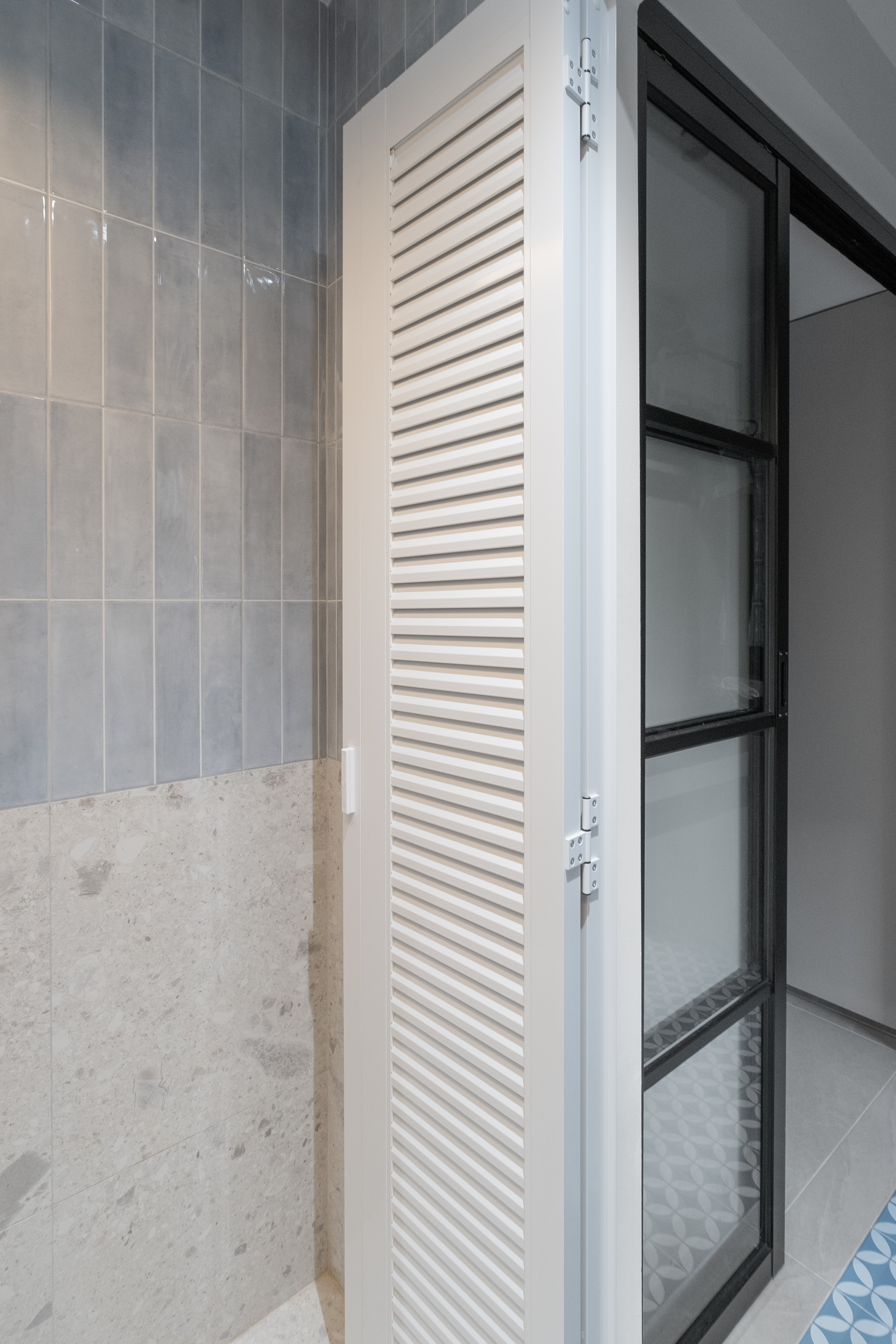 Tiny Guest Bathroom Redesign with Watercolor Blue and Grey Accents - Gray tiled wall, white louvered door, modern bathroom