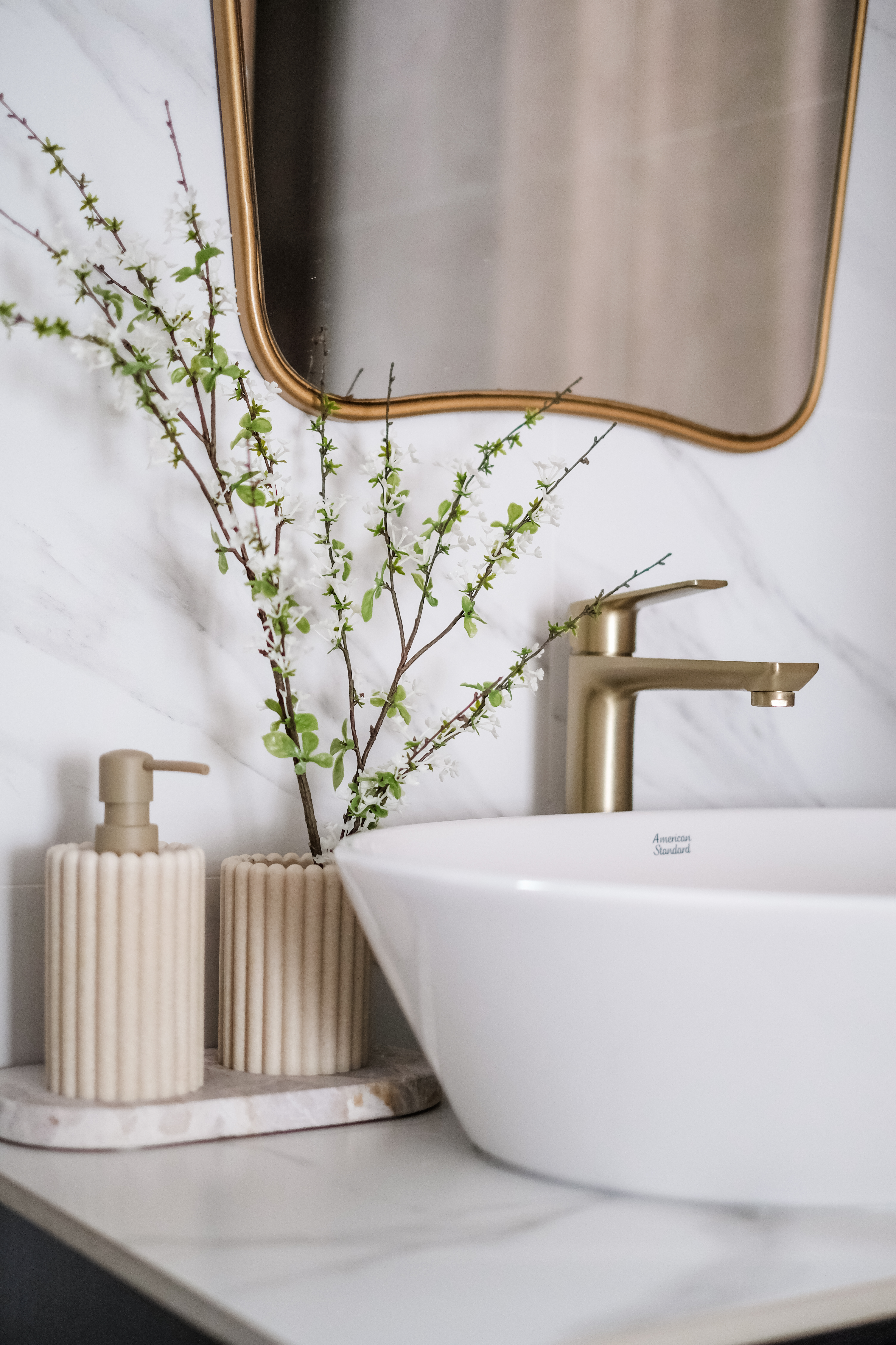 Sunlit Elegance: A Modern Bathroom Designed for Timeless Durability - White marble countertop, gold faucet, modern bathroom