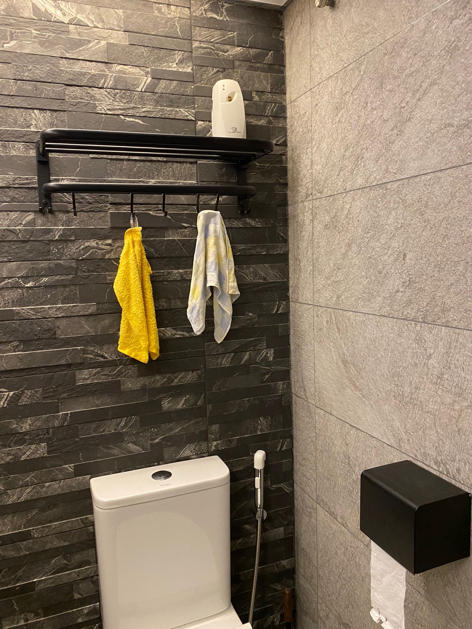 Our bathrooms: Resort-style relaxing sanctuaries - Dark gray marble tiles, modern bathroom, black metal shelf, yellow towel