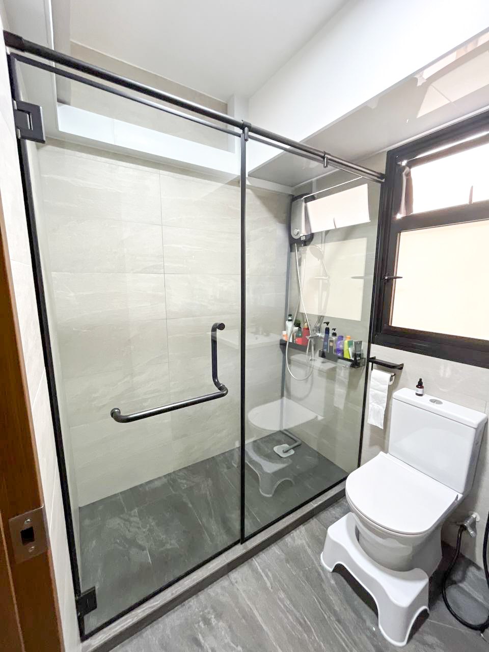 Simple and Calm Minimalist Toilet - Glass-enclosed shower, white toilet, modern bathroom, tiled floor, black metal frame