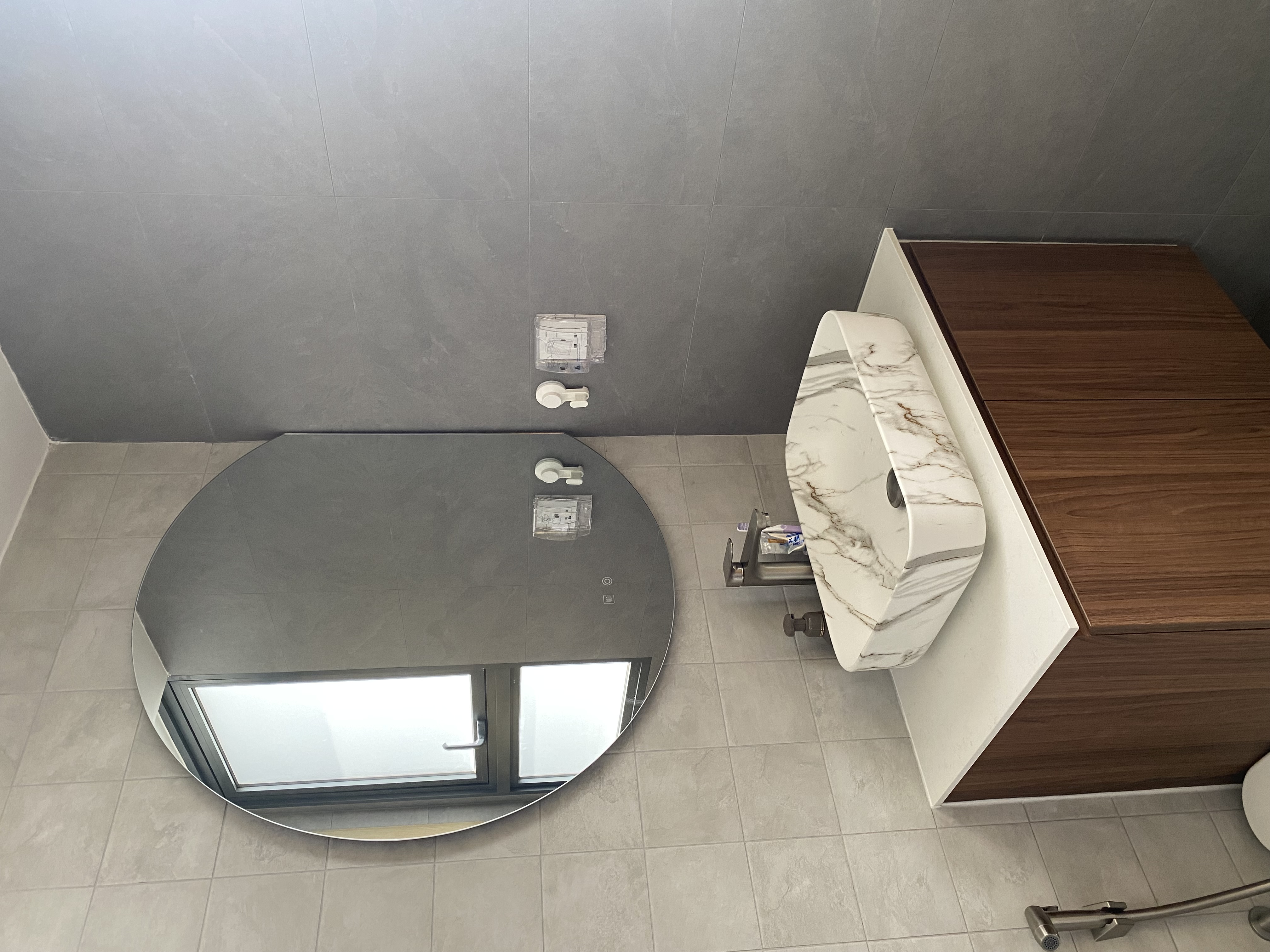 Moody and textured bathrooms in 50 shades of grey - Grey tiled walls, modern bathroom, round mirror, white toilet, marble