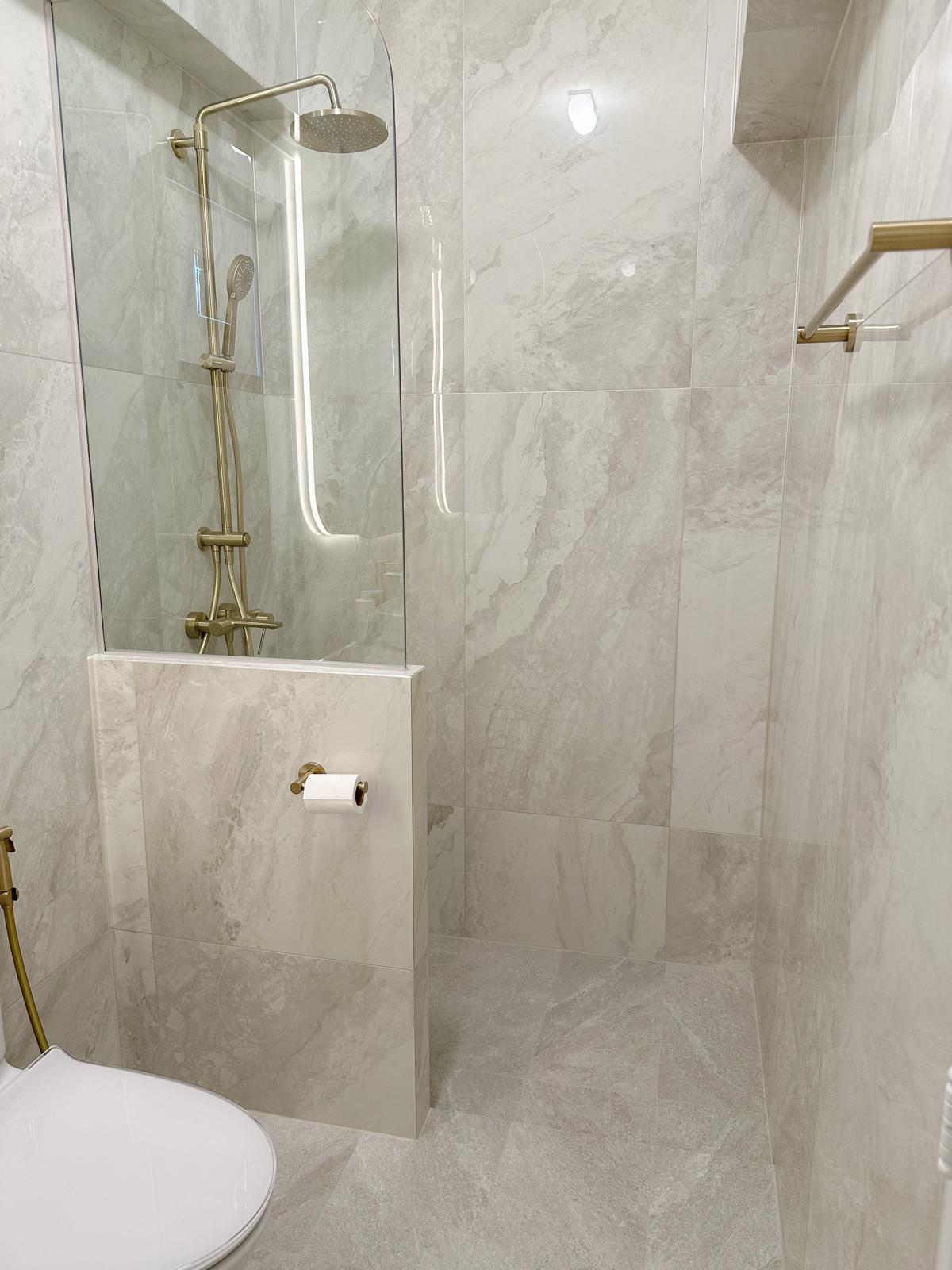 Master bath: Recreating the luxe hotel experience (w a hidden feature) - Glass-enclosed shower with gold fixtures, marble