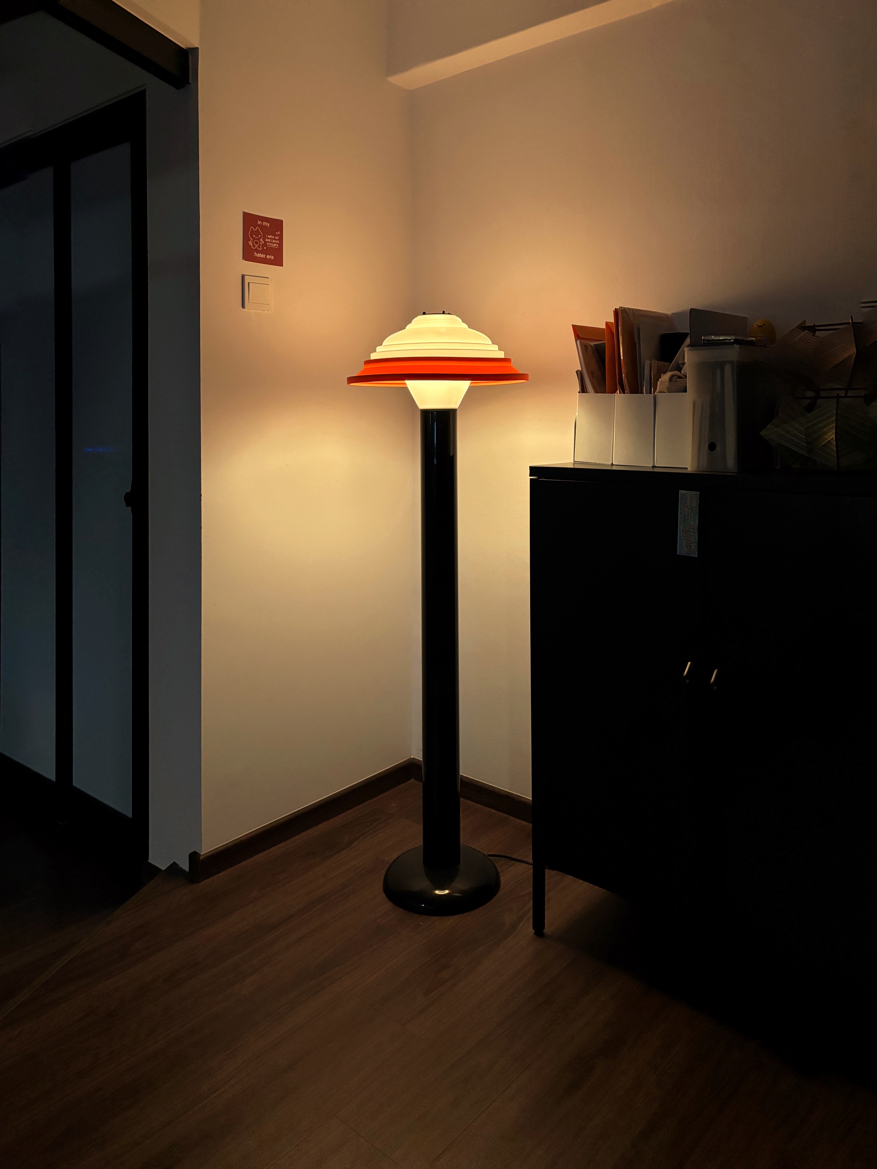6 types of Ambient Lights for Cosy Vibes  - Modern floor lamp with orange shade, sleek black base, warm ambient light