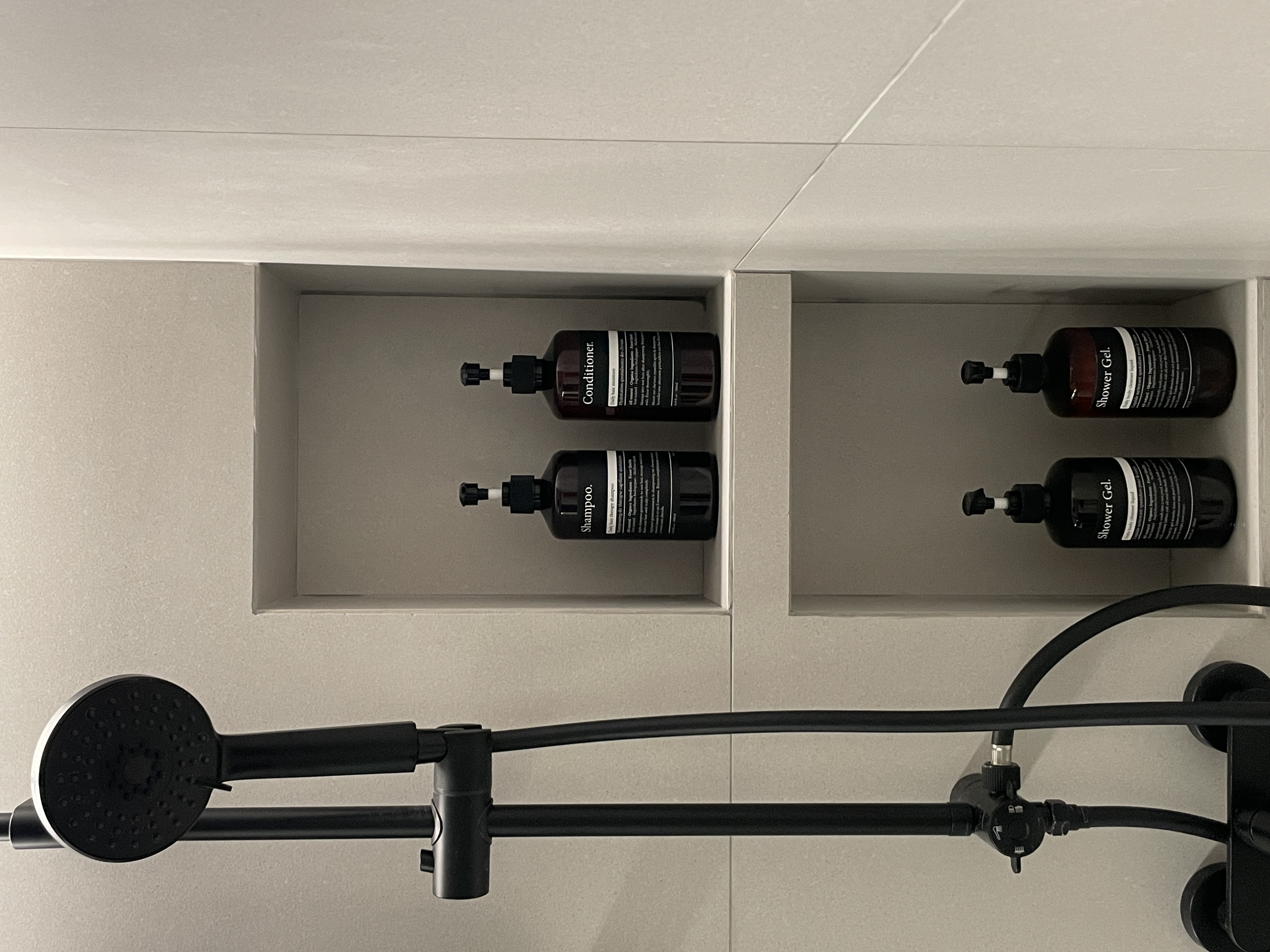 Elevate Your Space: Hotel-Inspired Bathrooms Transformation - Shower gel bottles, black and brown, neatly arranged