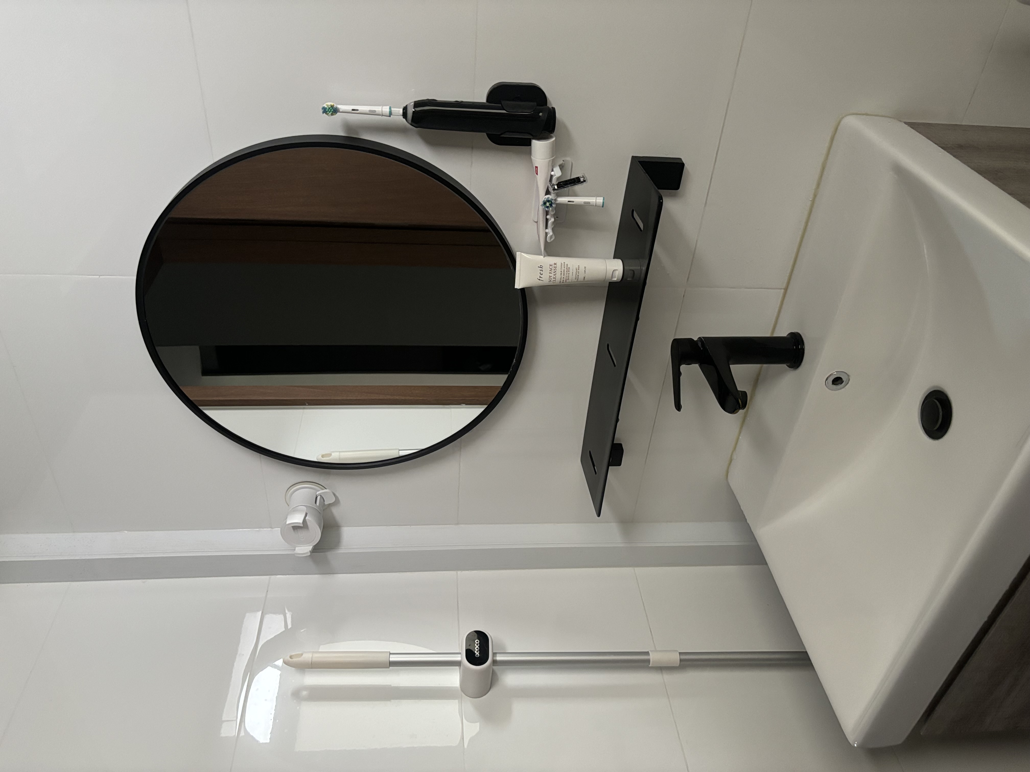 Minimal Bathroom without Breaking the Bank - Round mirror, black frame, white wall, bathroom vanity, white sink, black