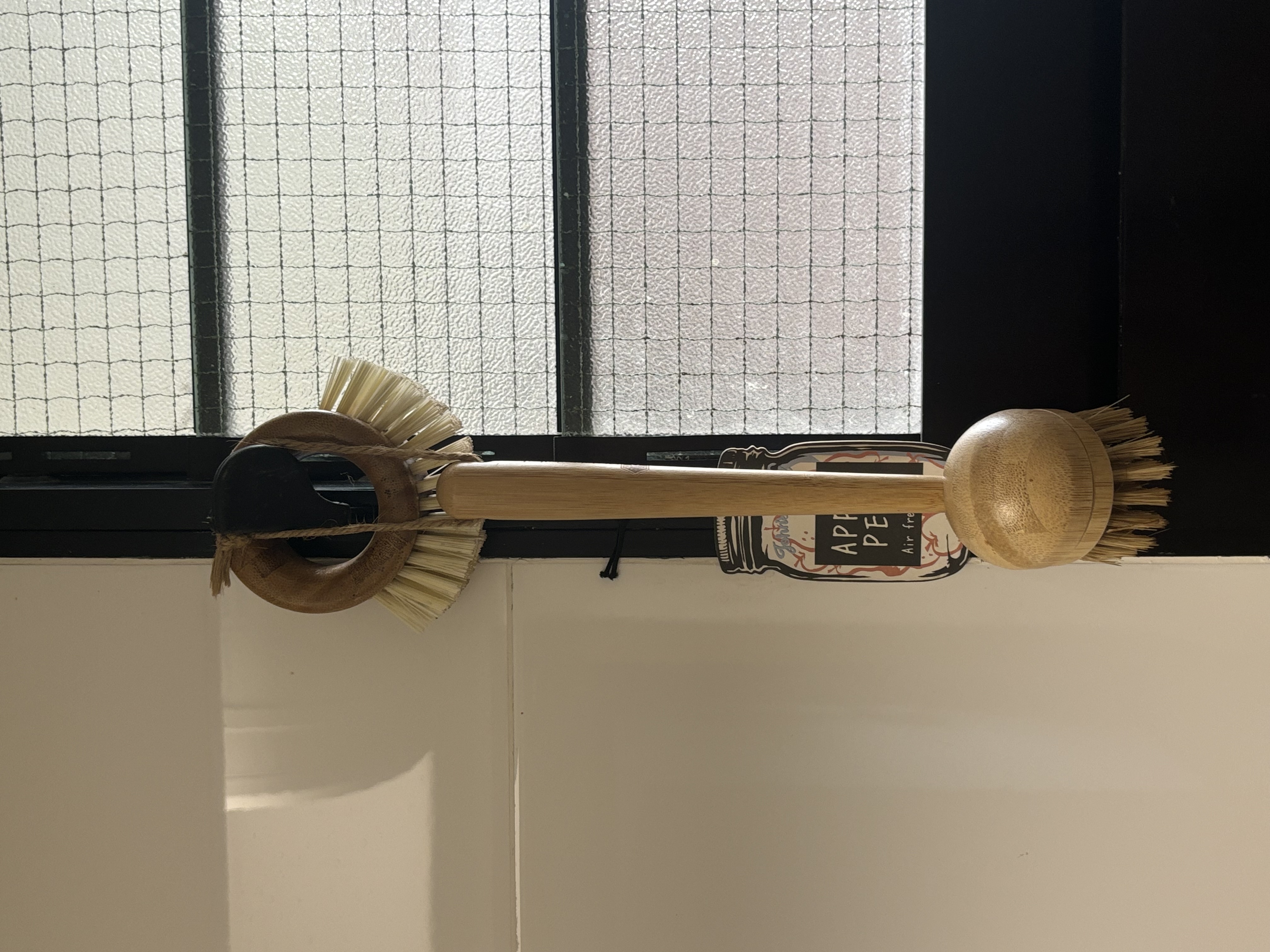 Minimal Bathroom without Breaking the Bank - Broom with wooden handle and straw bristles, hanging on a window ledge, natural