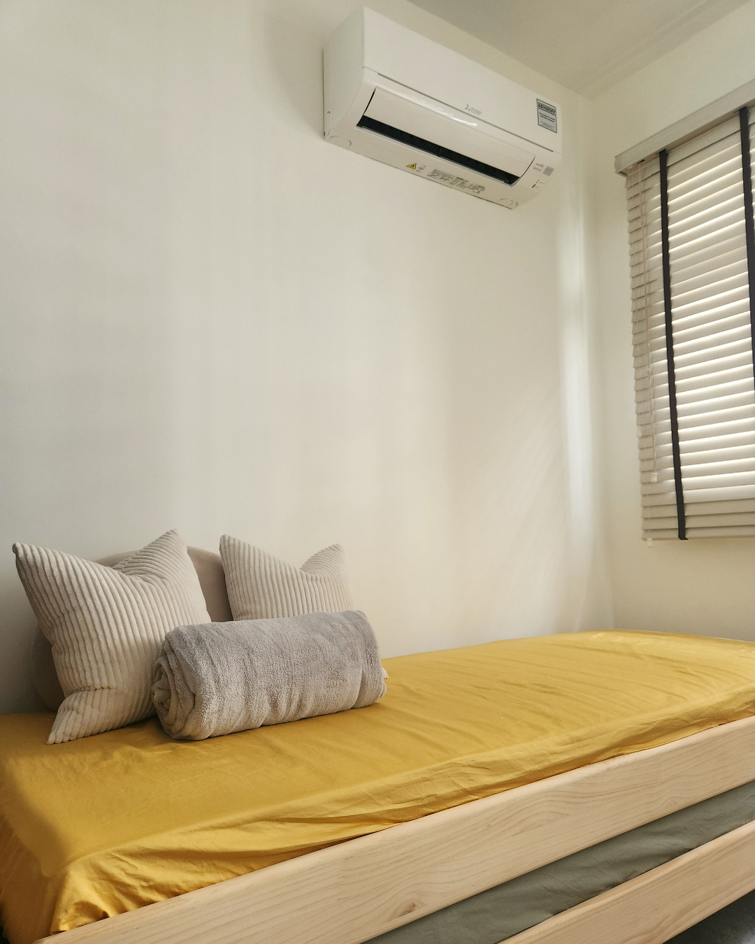Personal Touches: Bringing Warmth to Our Guest Room - White and beige striped pillows, yellow bedspread, wooden frame bed