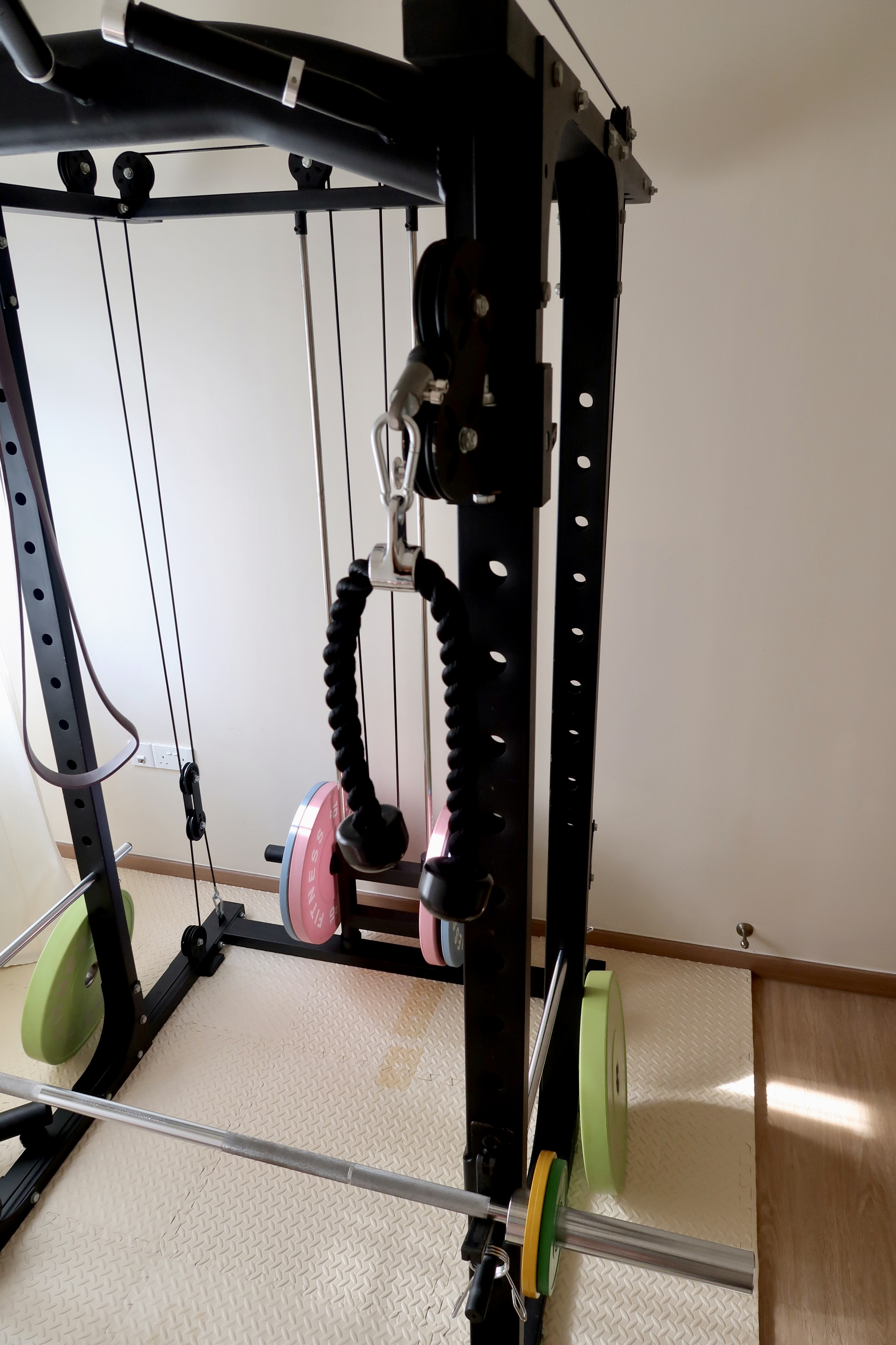Under $1000 Home Gym: Versatile Gym Setup with Fun Colours! - Black exercise machine, green weight plates, pink weight
