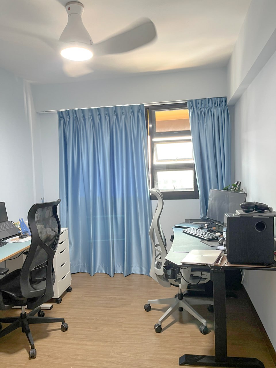 Home Office: White vs Black - Office space with ergonomic chair and desk, blue curtains framing a window, ceiling fan with a