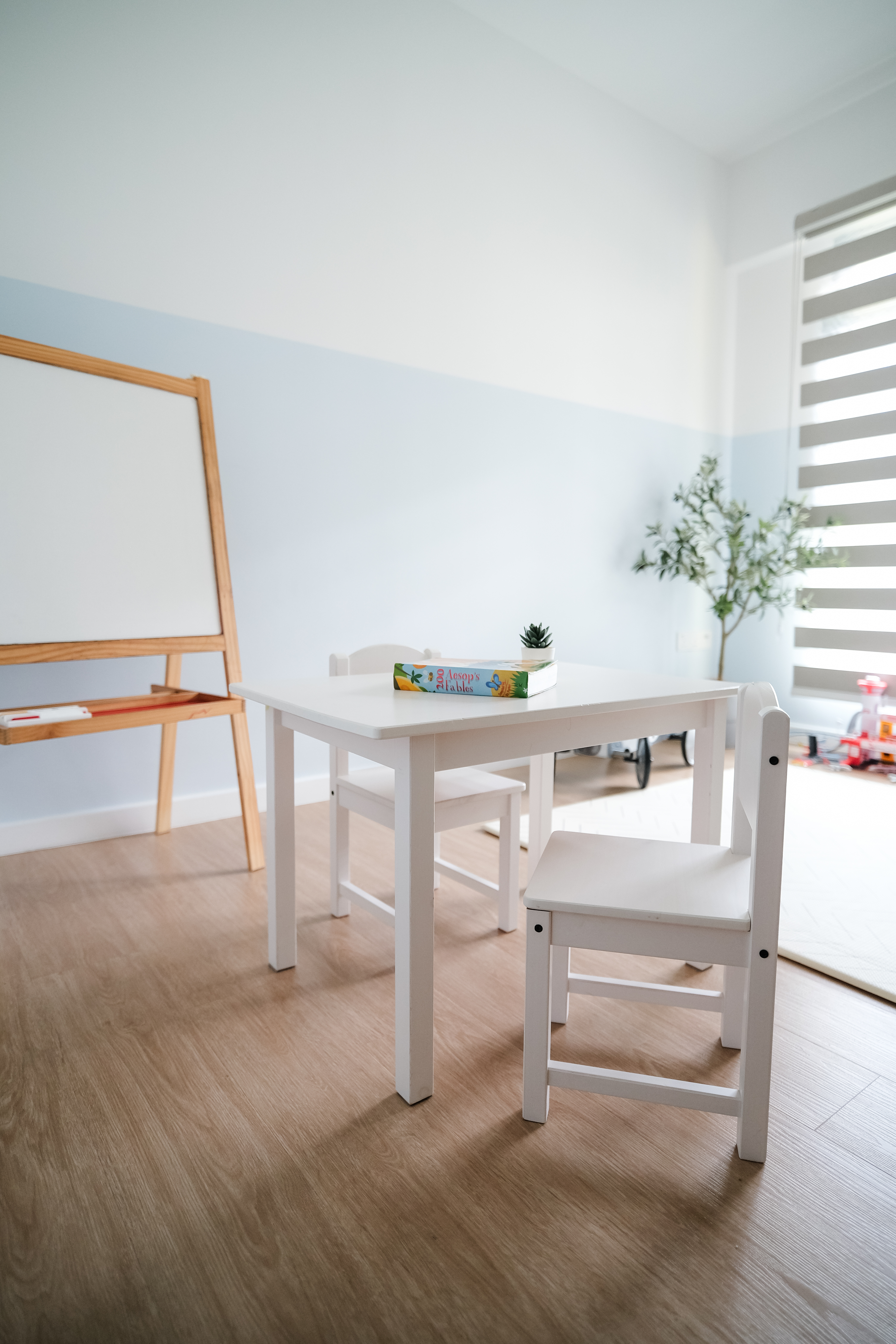 Playroom Design with Loose Furniture for Maximum Space and Flexibility - White wooden easel, light blue walls, wooden floor