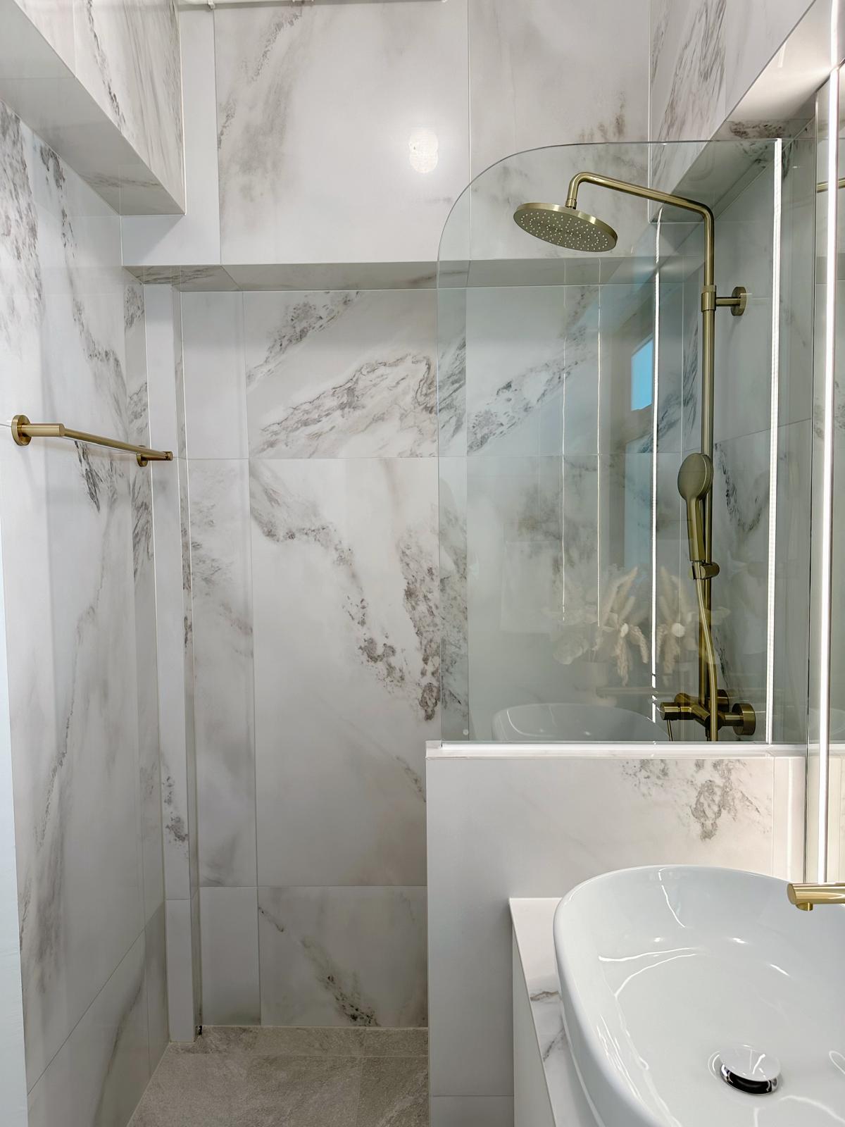 Guest bath: Marble, gold & sliding doors - White marble tiles, gold fixtures, modern design, sleek sink, glass shower
