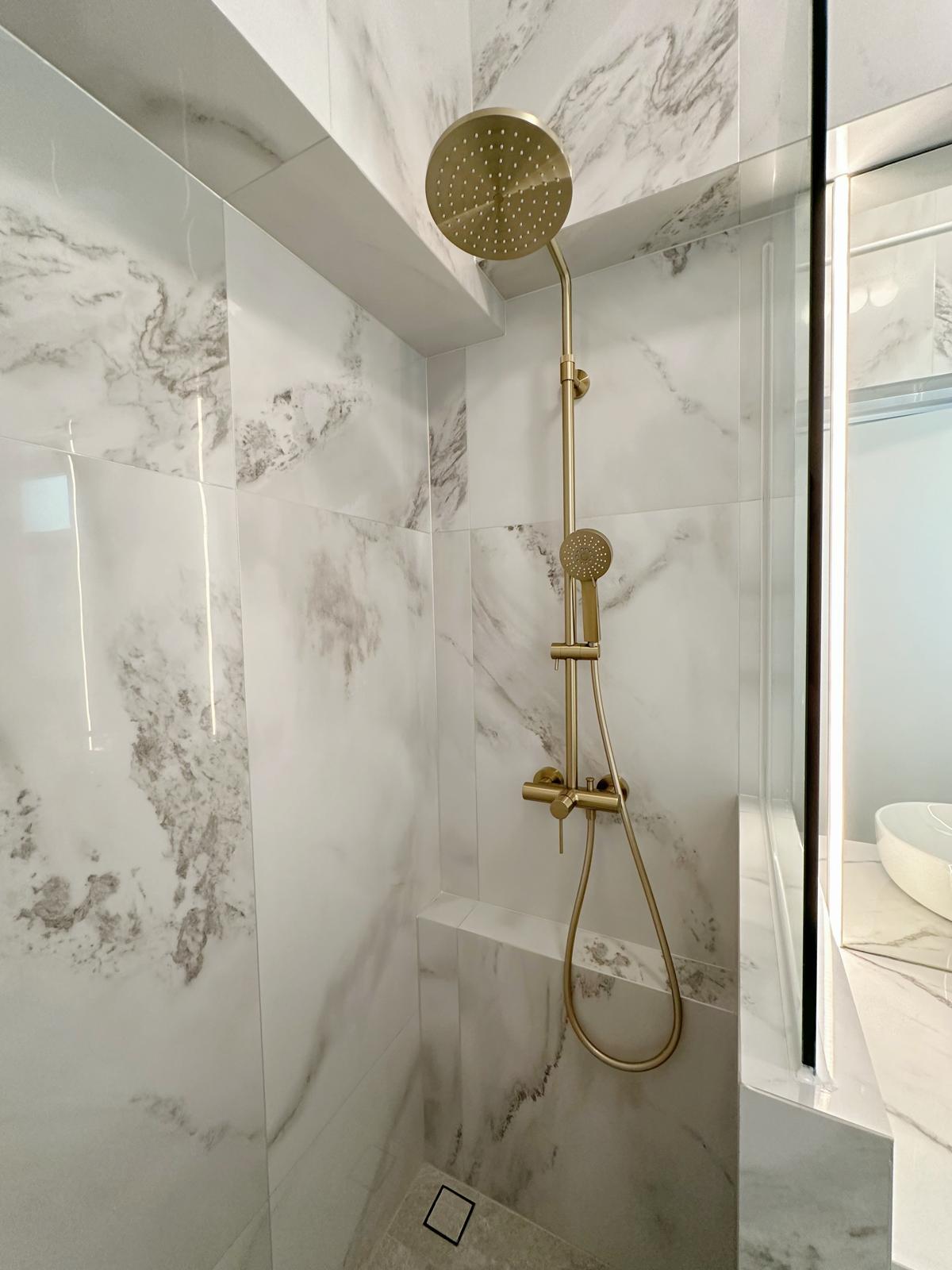 Guest bath: Marble, gold & sliding doors - Marble-patterned walls, gold showerhead, modern design, luxurious bathroom, sleek