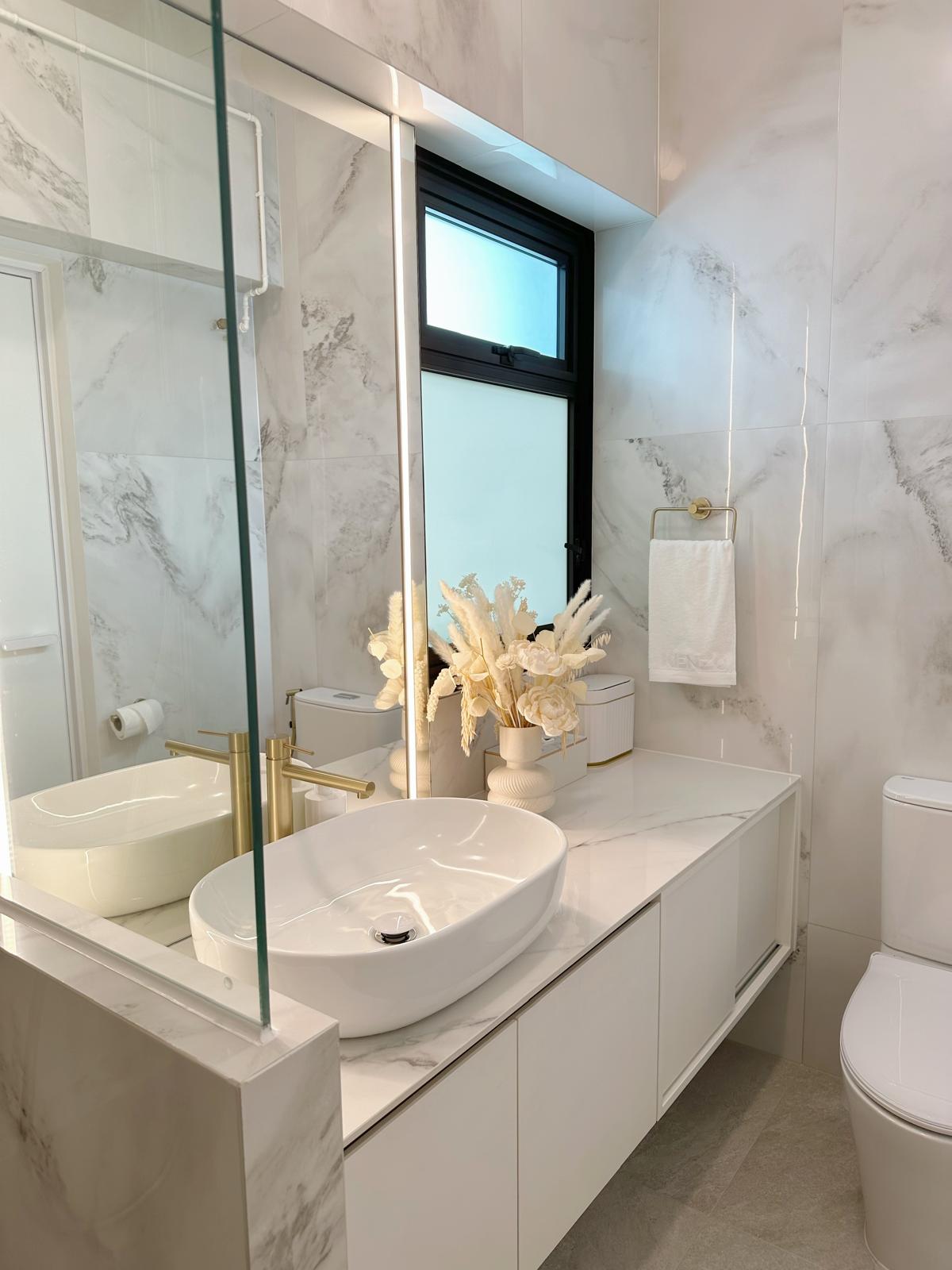 Guest bath: Marble, gold & sliding doors - White marble bathroom vanity, modern design, sleek fixtures, large mirror, glass