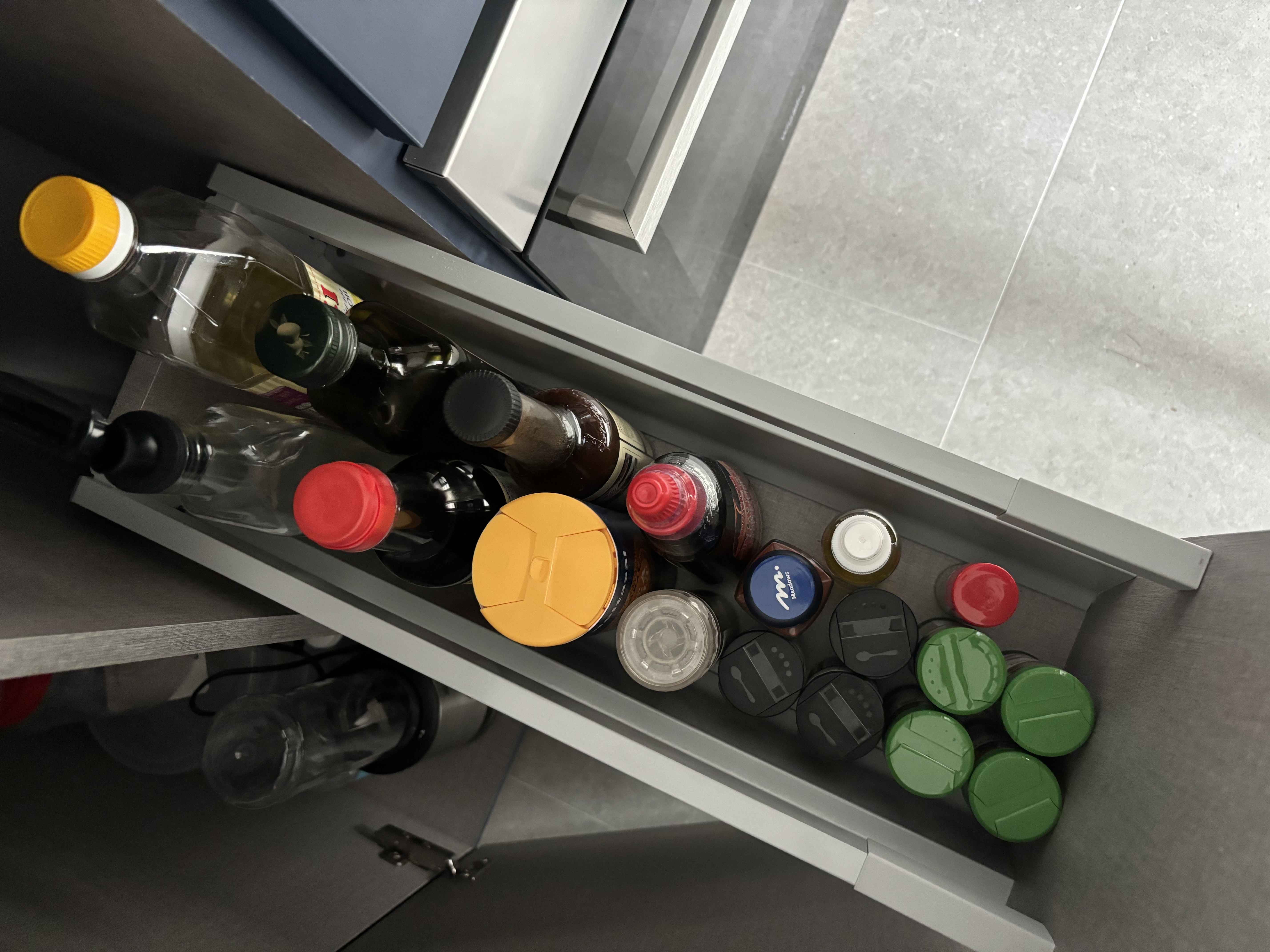 Simple home organisation tips you can try! - Organized kitchen drawer, neatly arranged bottles, diverse bottle types