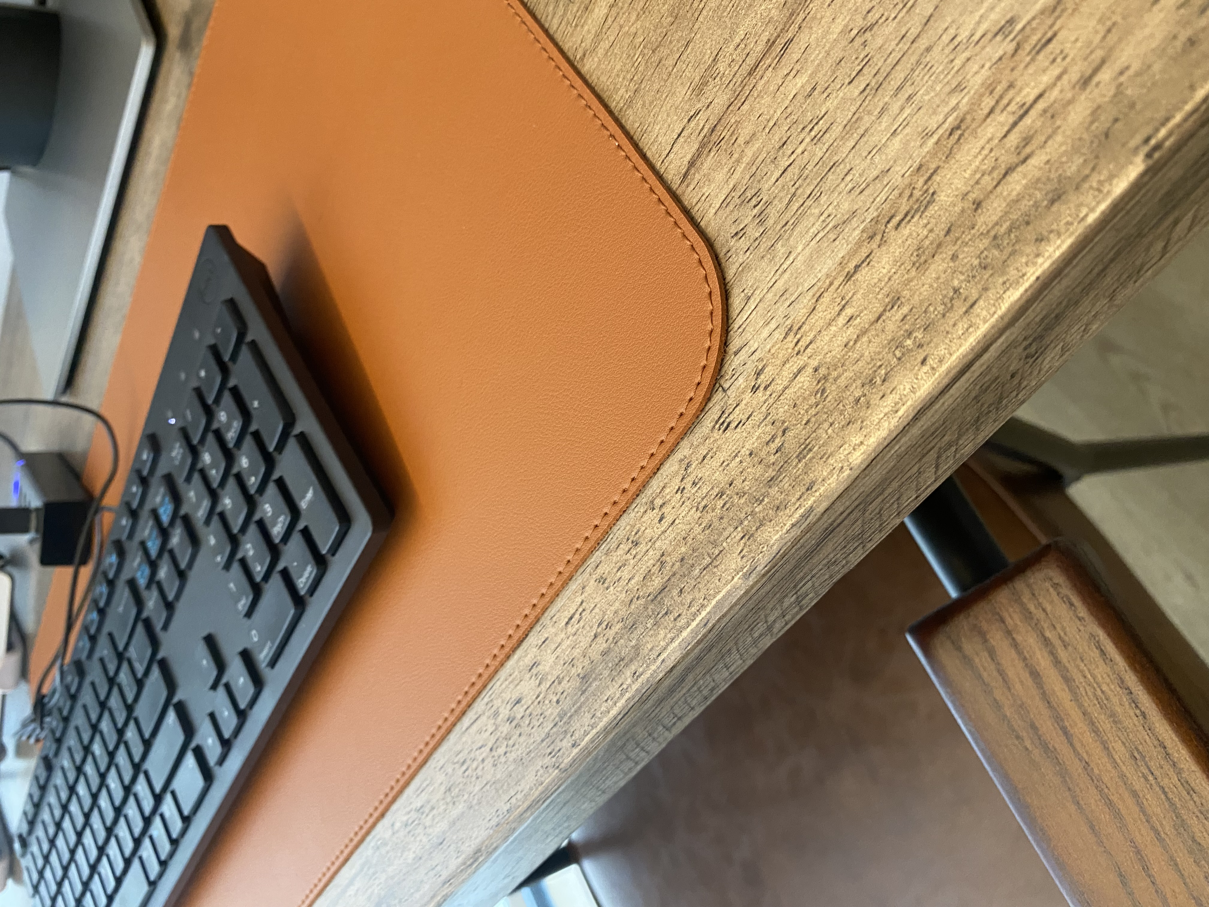 Minimalist work room for 2 with no built-ins - Wooden desk, black keyboard, leather mouse pad, close-up view, ergonomic