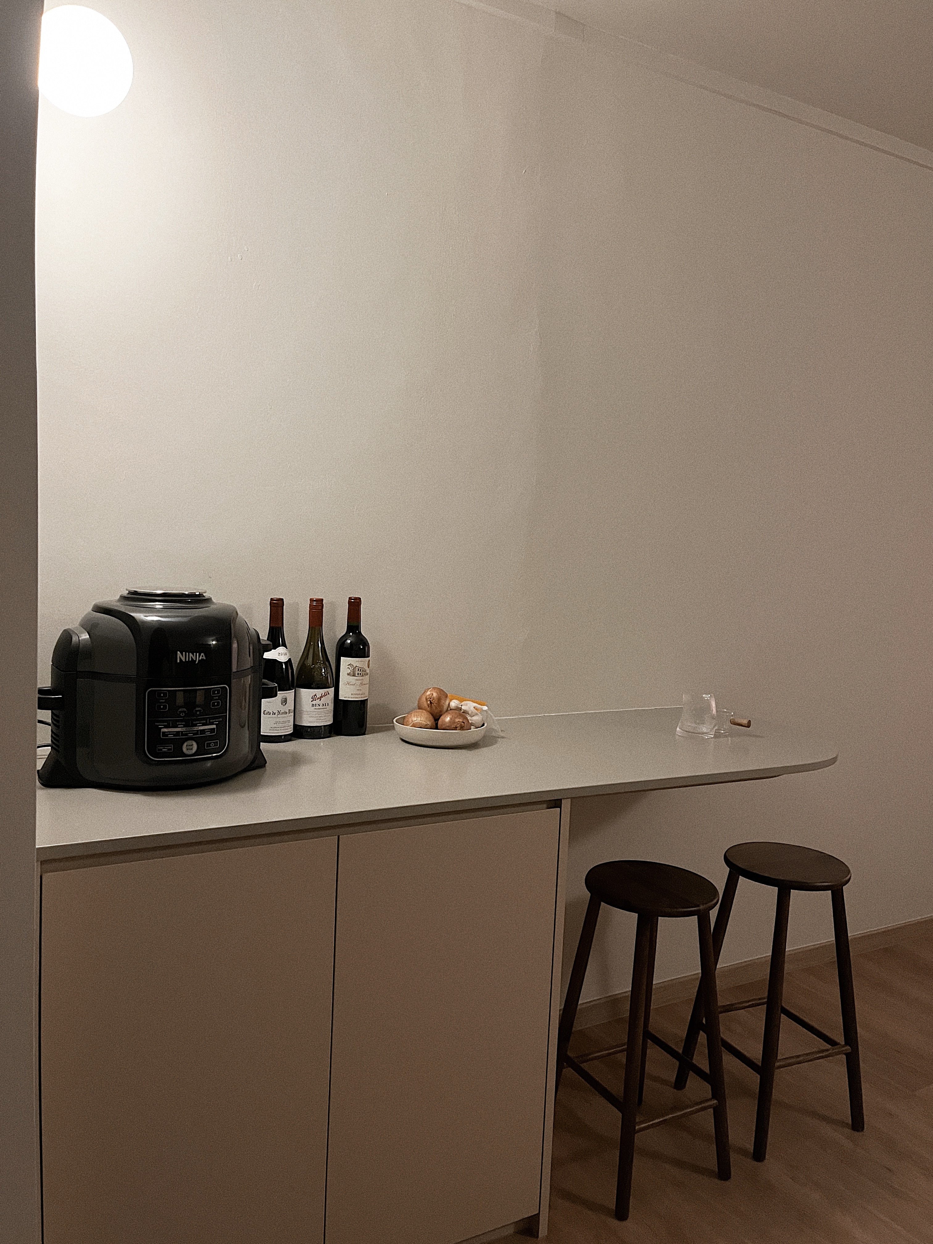 Top Investments for Modern Living - Ninja kitchen appliance, wine bottles, wooden stools, minimalist decor, light fixture